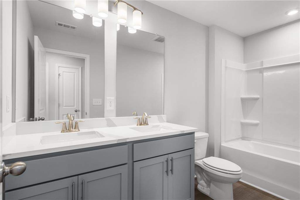 Modern double vanity bathroom with gray cabinets, white quartz counters, gold faucets in The Monroe B, Emerson, Georgia