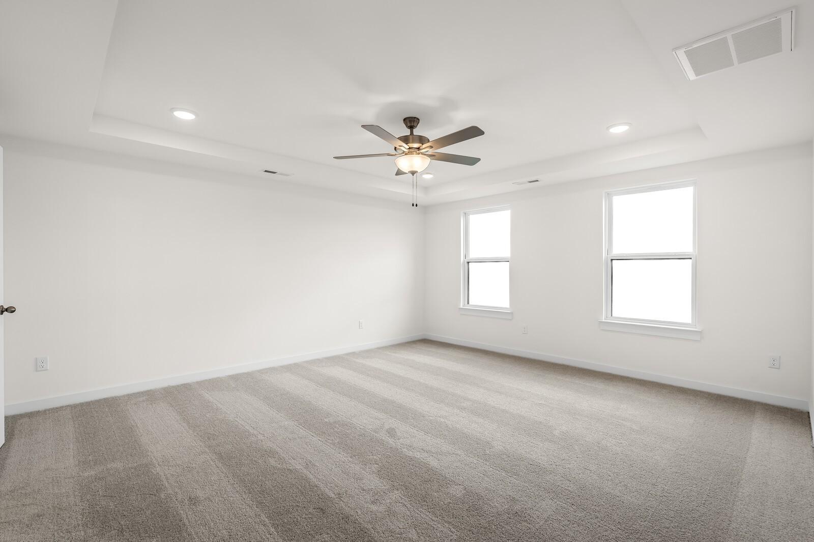 Spacious bedroom with tray ceiling and ceiling fan in The Henry C floor plan by Davidson Homes in Mt. Juliet, Tennessee.