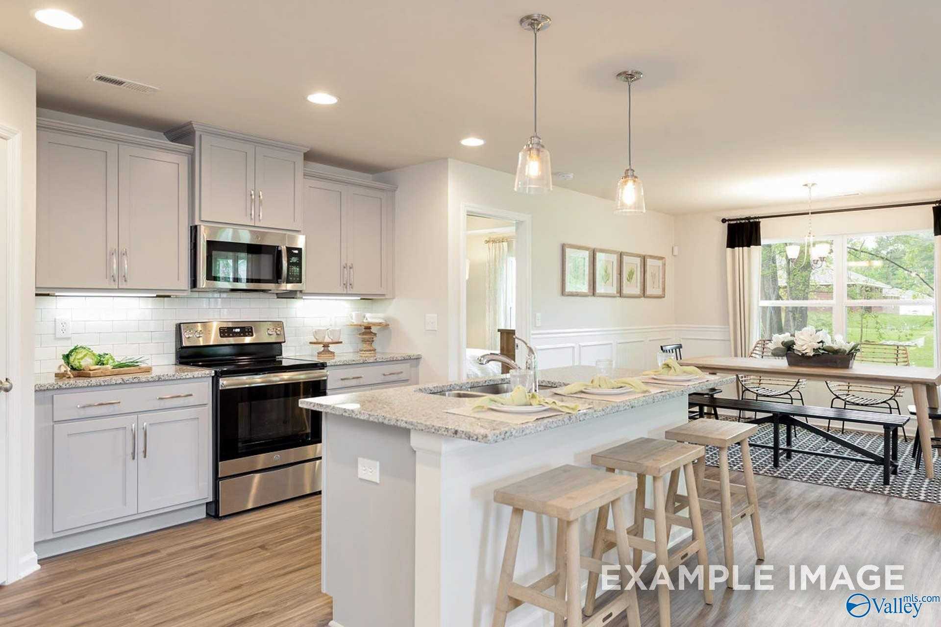Modern open-concept kitchen with gray cabinets, stainless appliances, island bar, and dining nook in Davidson Homes The Franklin B, Hazel Green, Alabama