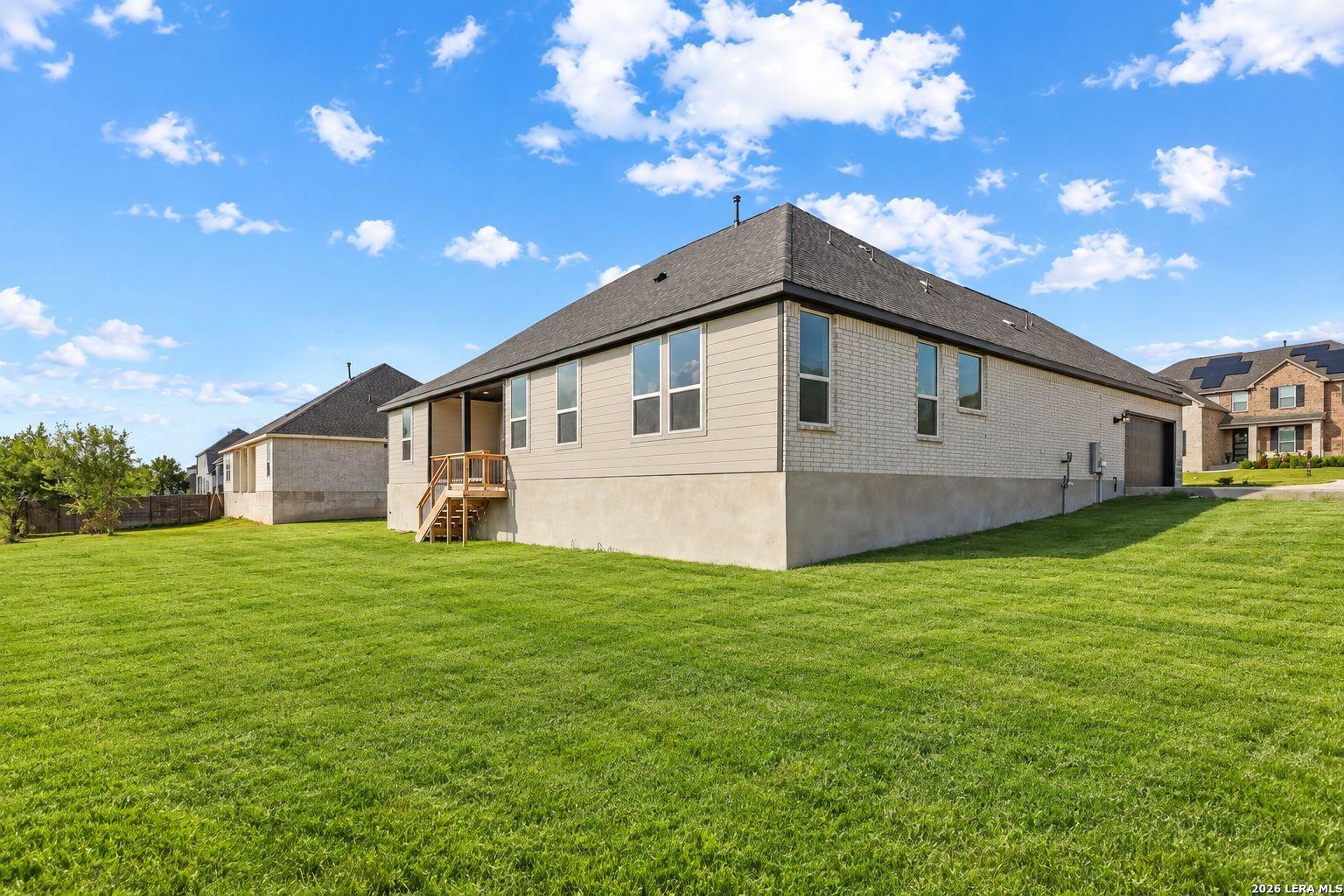 Rear exterior of Davidson Homes' The Foster E with large fenced backyard, covered patio, and 3-car garage in Potranco Oaks, Castroville, TX