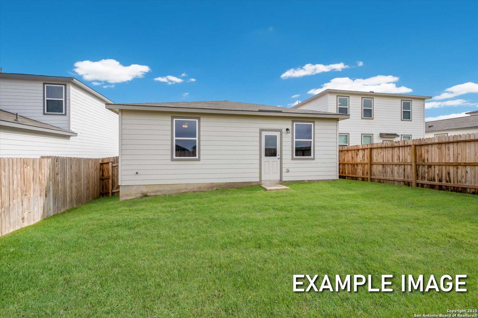 Backyard of single-story The Comal B home featuring covered patio, fenced green lawn, and beige exterior in Agave, San Antonio, Texas