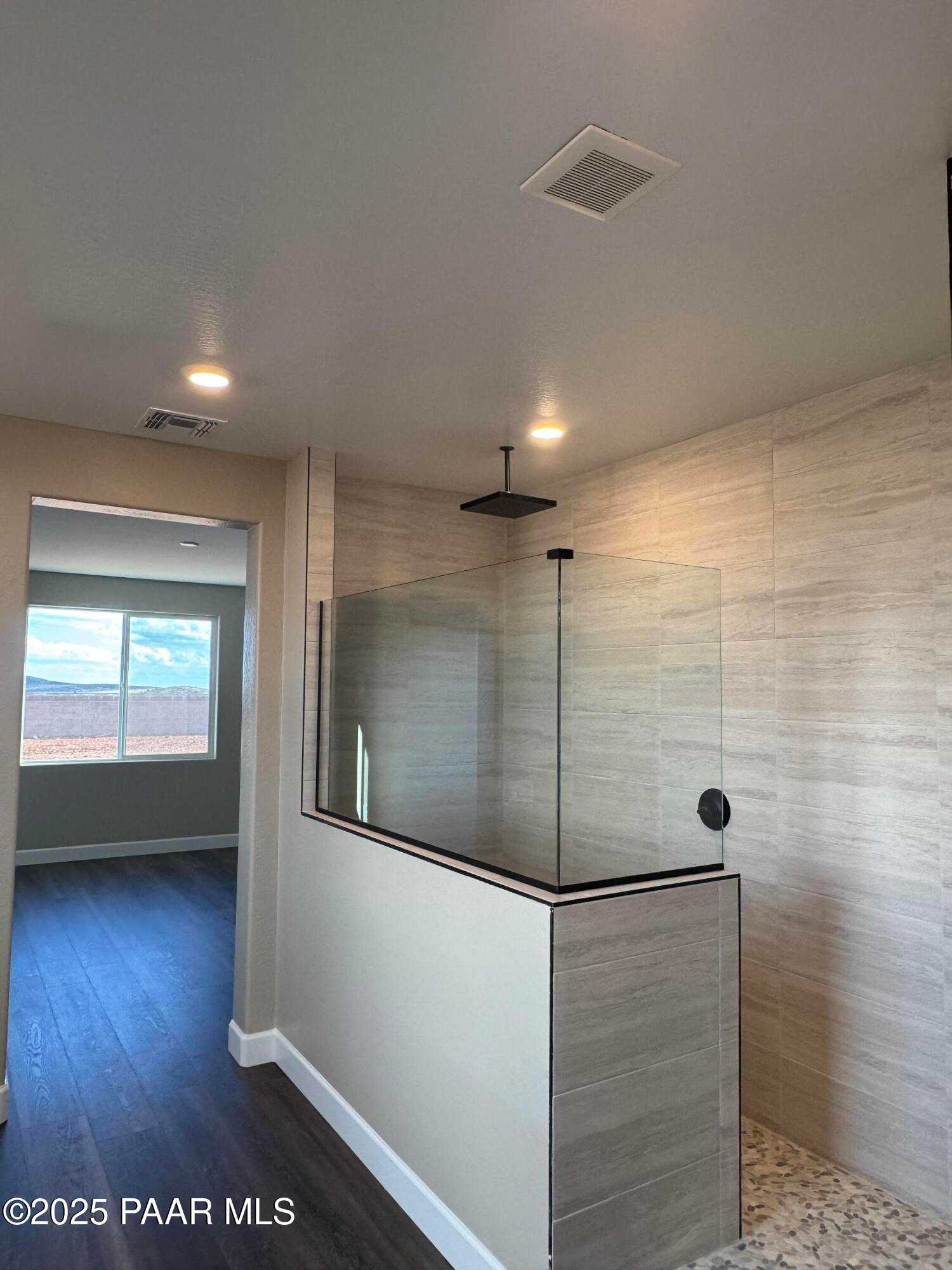 Modern walk-in shower with glass enclosure, rain head, and tile walls in master bath of Evermore Homes Sunrise A, Prescott Valley, AZ
