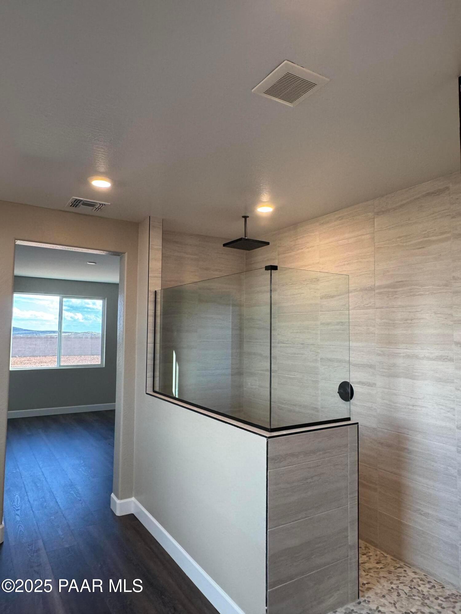 Modern walk-in shower with glass enclosure, rain head, and tile walls in master bath of Evermore Homes Sunrise A, Prescott Valley, AZ