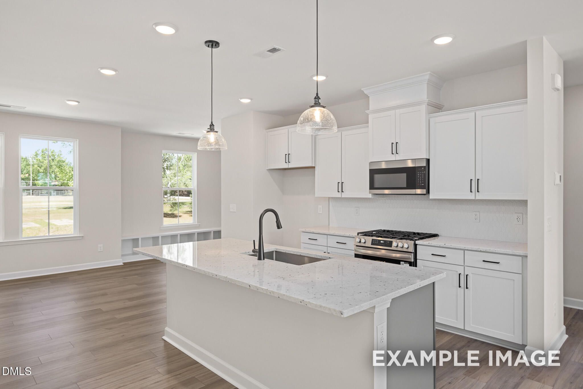 Modern kitchen with white cabinets, granite island, and stainless appliances in The Mitchell floor plan at Camden Park.
