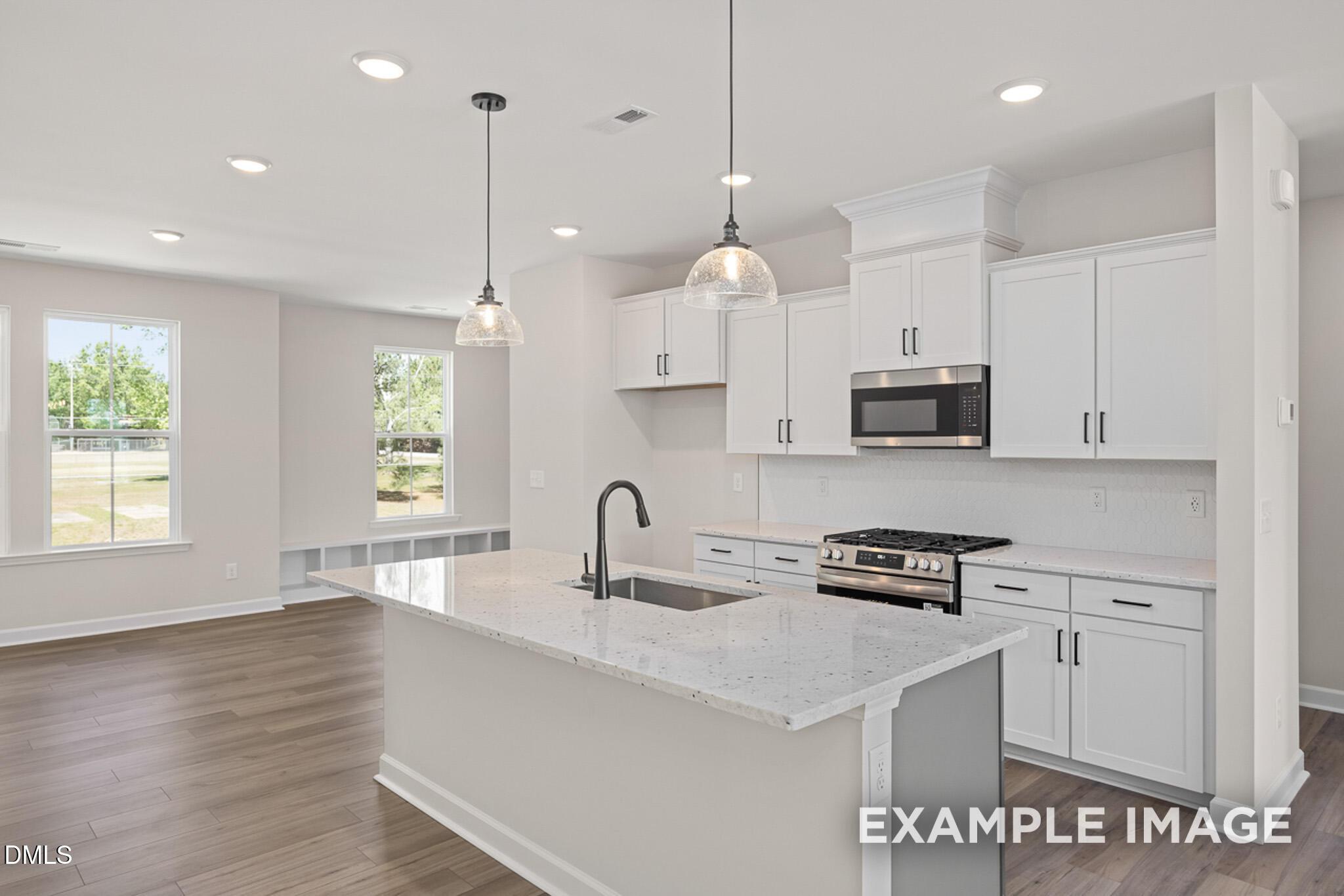 Modern kitchen with white cabinets, granite island, and stainless appliances in The Mitchell floor plan at Camden Park.