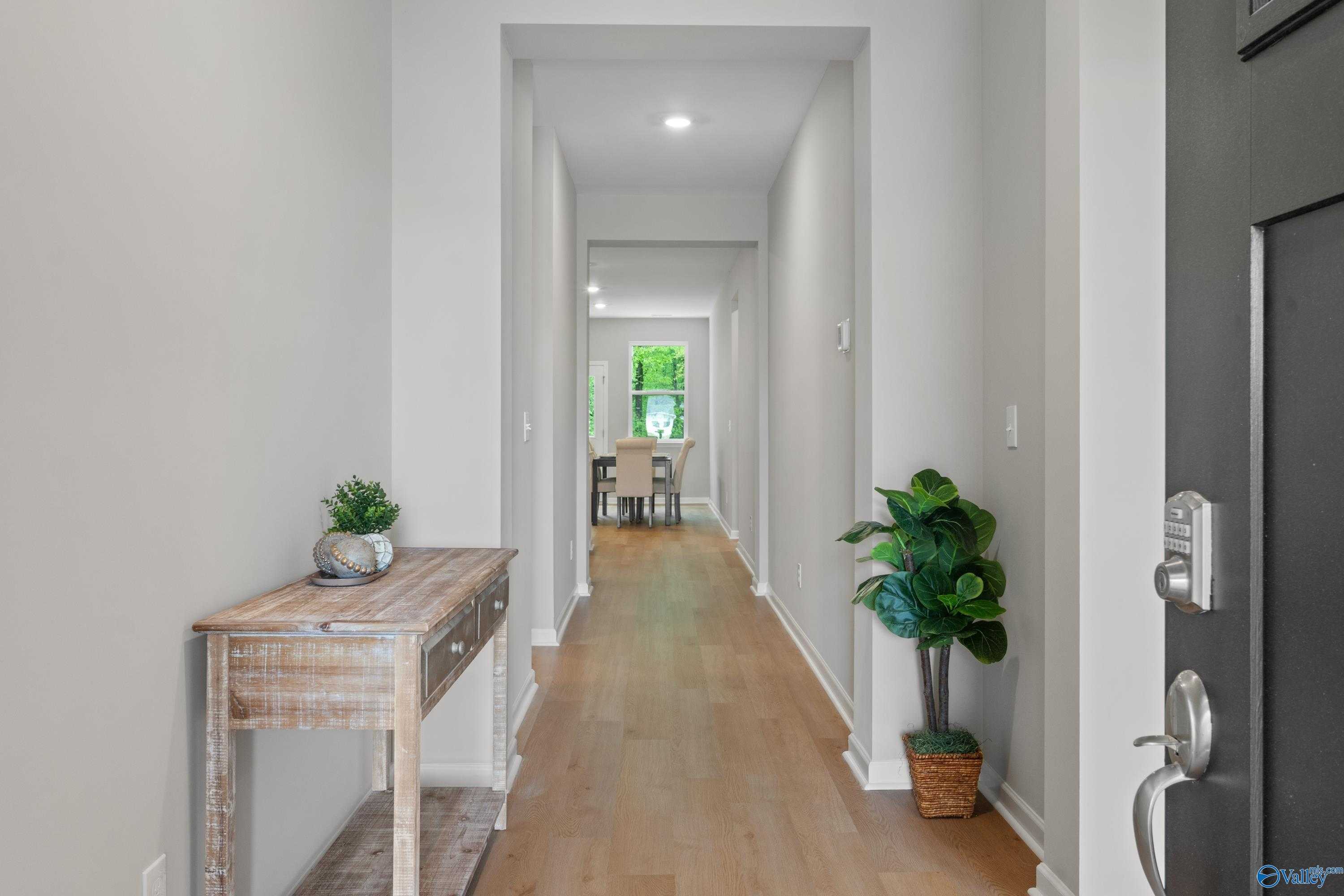 Bright entry hallway with wood console table, potted plants, and dining nook in Davidson Homes The Luna, Hazel Green, Alabama