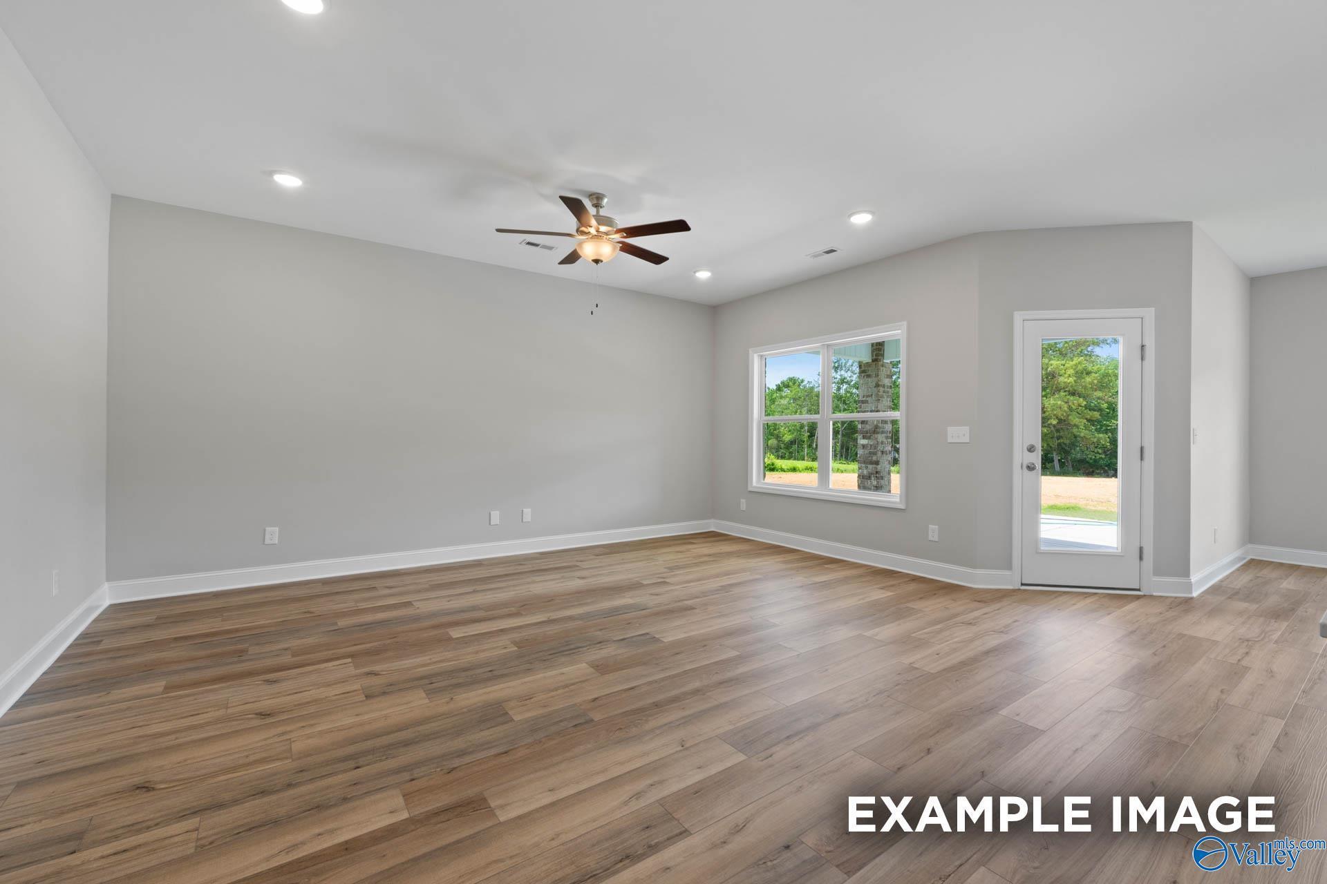 Spacious living room with gray walls, luxury vinyl plank floors, ceiling fan, large windows, and glass door in 4-bedroom Everett B home, Athens, Alabama