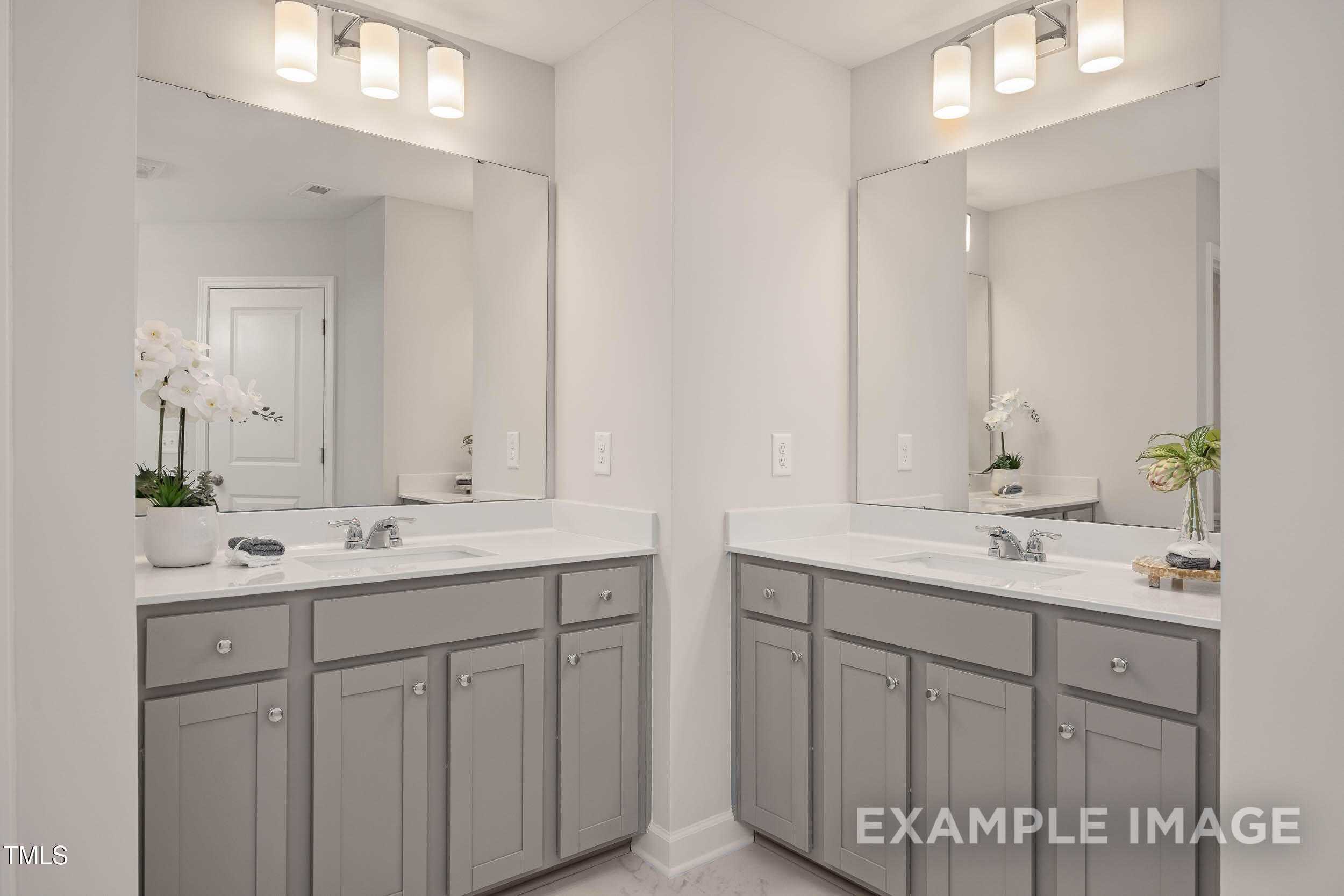 Elegant double vanity master bathroom with gray shaker cabinets, white quartz counters, and orchids in Davidson Homes The Graham, Fuquay-Varina, NC