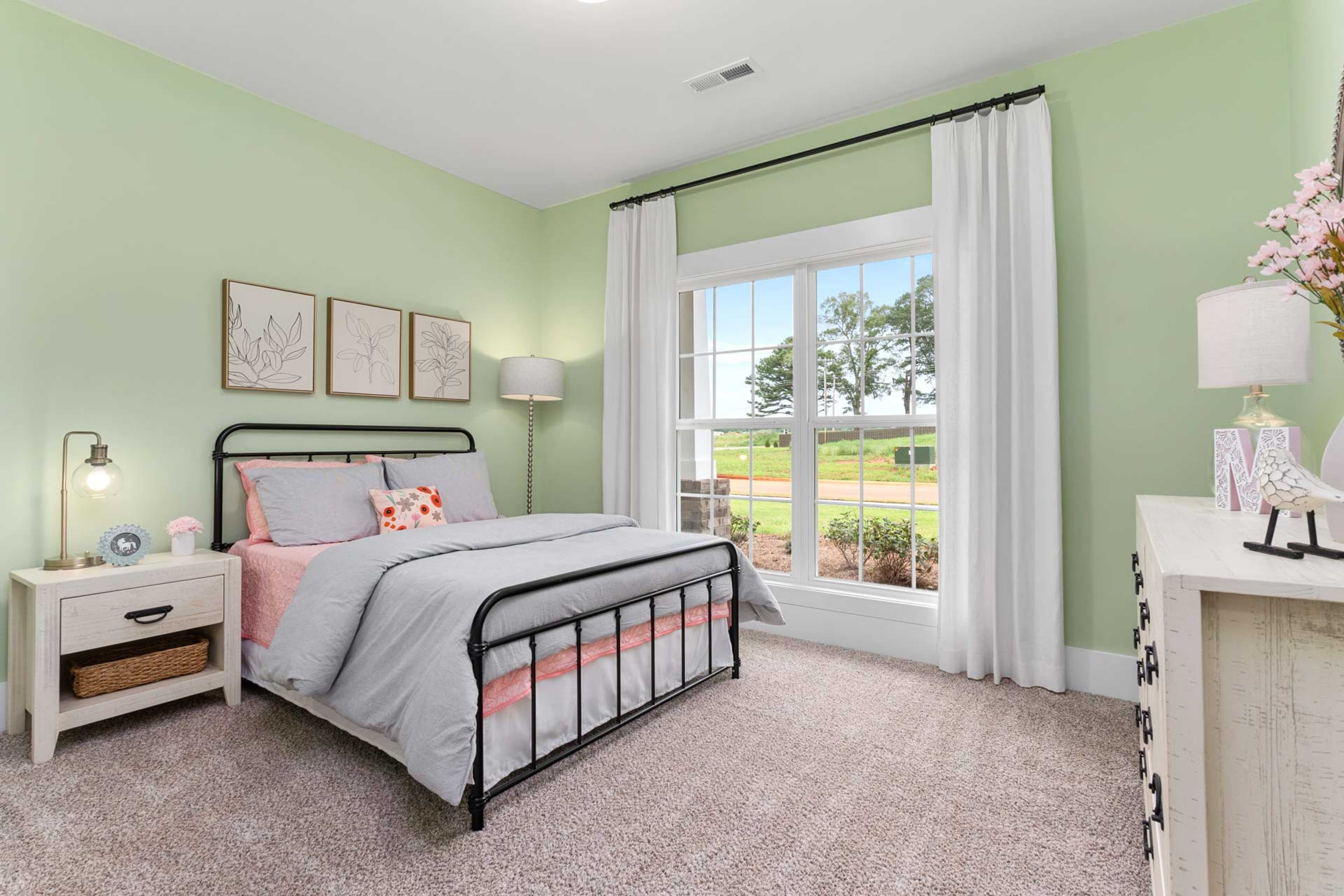 Charming mint green bedroom at The Meadows in Athens Alabama with pink bedding twin bed and garden view window