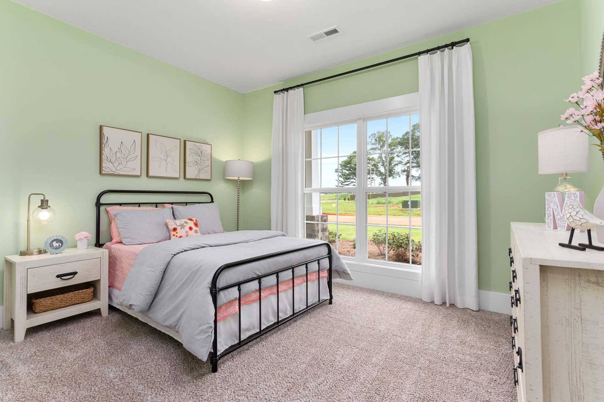Charming mint green bedroom at The Meadows in Athens Alabama with pink bedding twin bed and garden view window