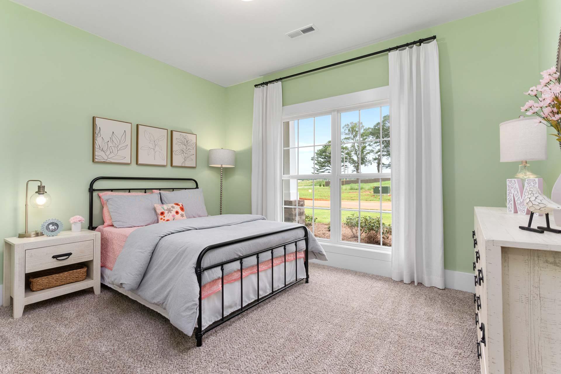 Charming mint green bedroom at The Meadows in Athens Alabama with pink bedding twin bed and garden view window