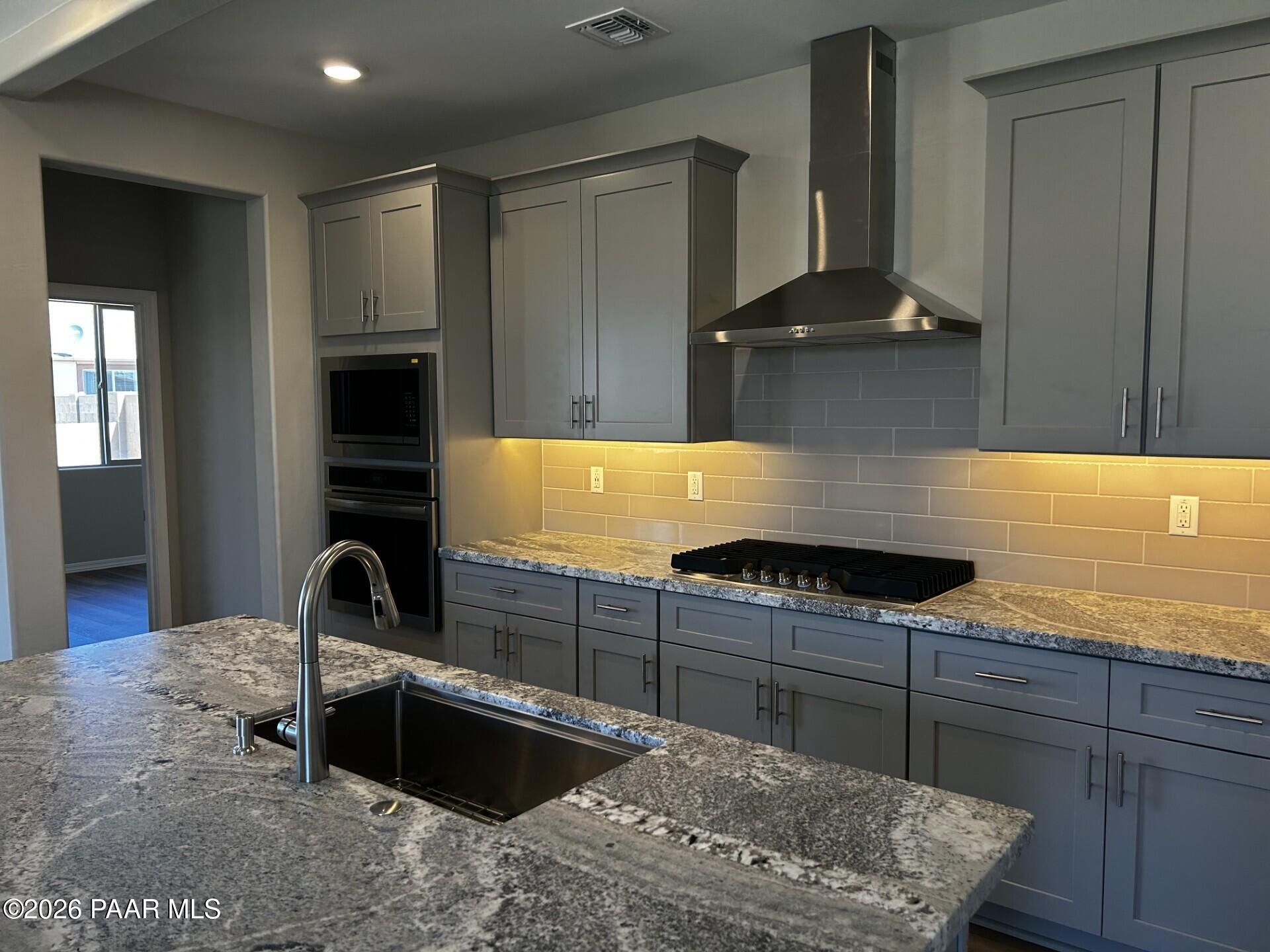 Modern gray shaker cabinets, granite island sink, stainless steel range and oven in The Frontier A kitchen, Prescott Valley, AZ
