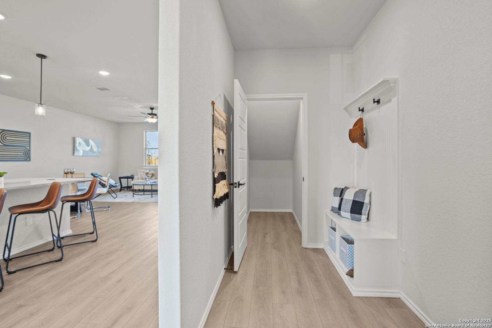 Spacious entryway with built-in bench, coat hooks, and wood floors opening to living area in Davidson Homes The Douglas C, Seguin, Texas