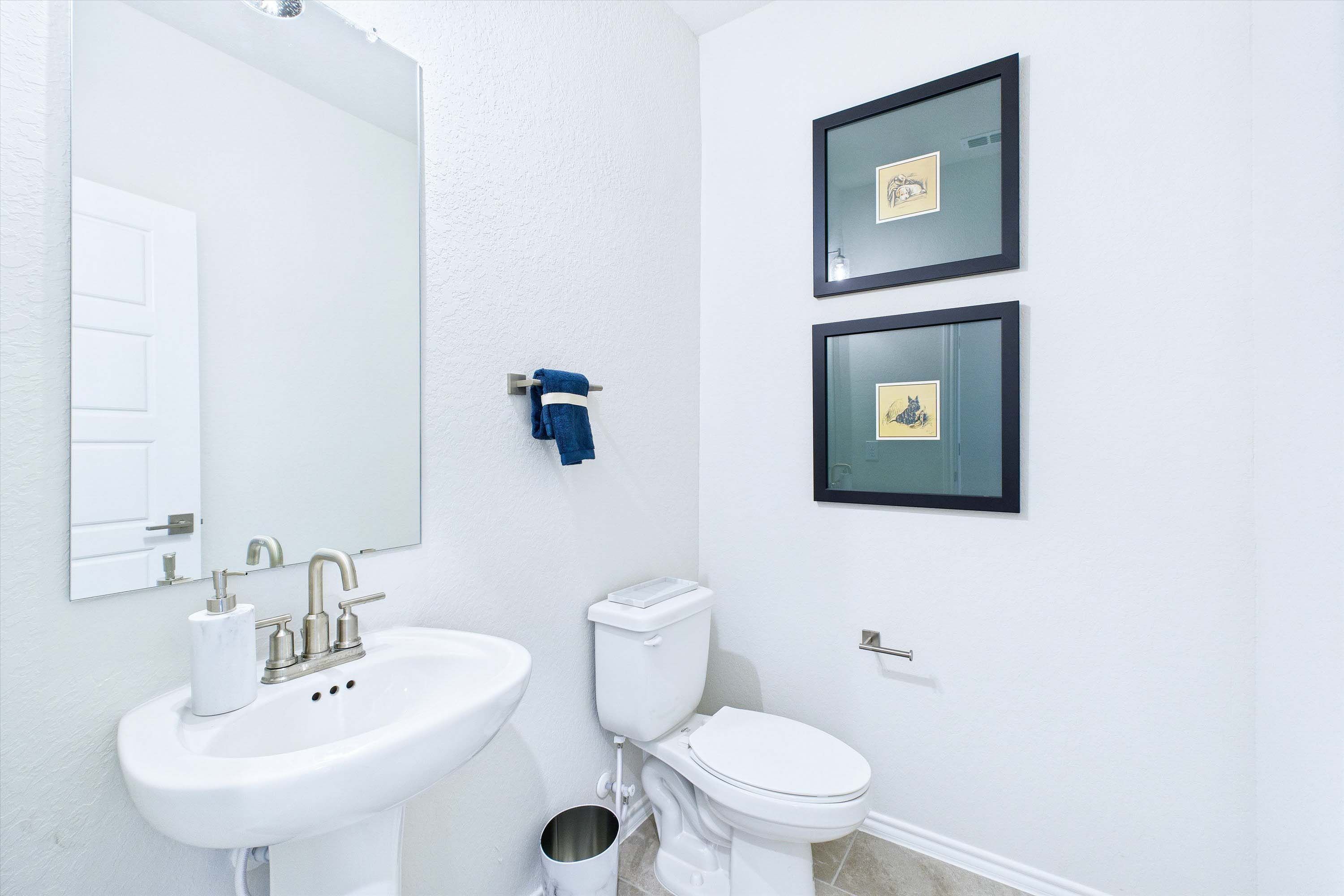 Bright powder room in The Gillian C featuring a pedestal sink, modern fixtures, and minimalist wall decor.