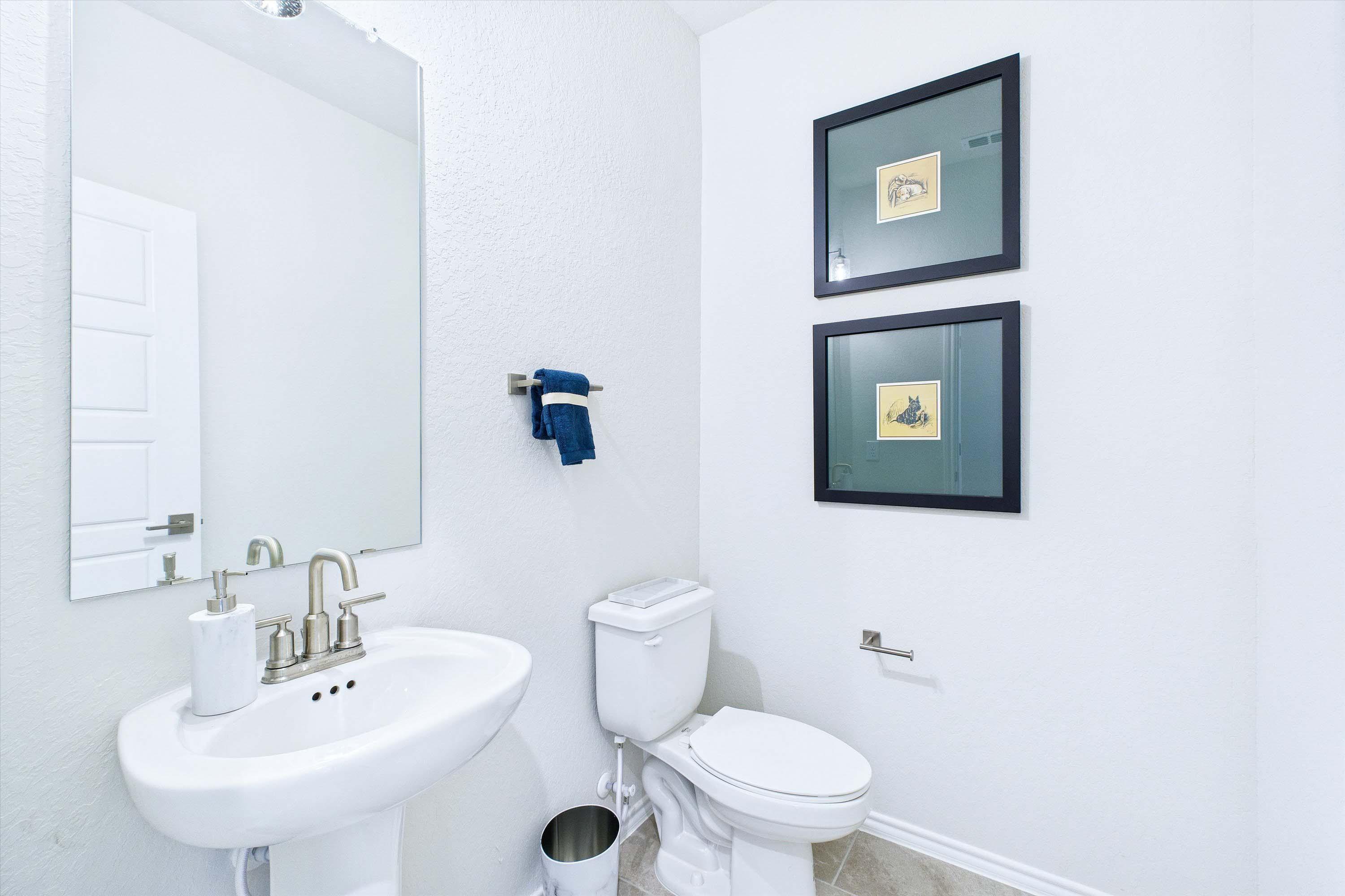 Bright powder room in The Gillian C featuring a pedestal sink, modern fixtures, and minimalist wall decor.