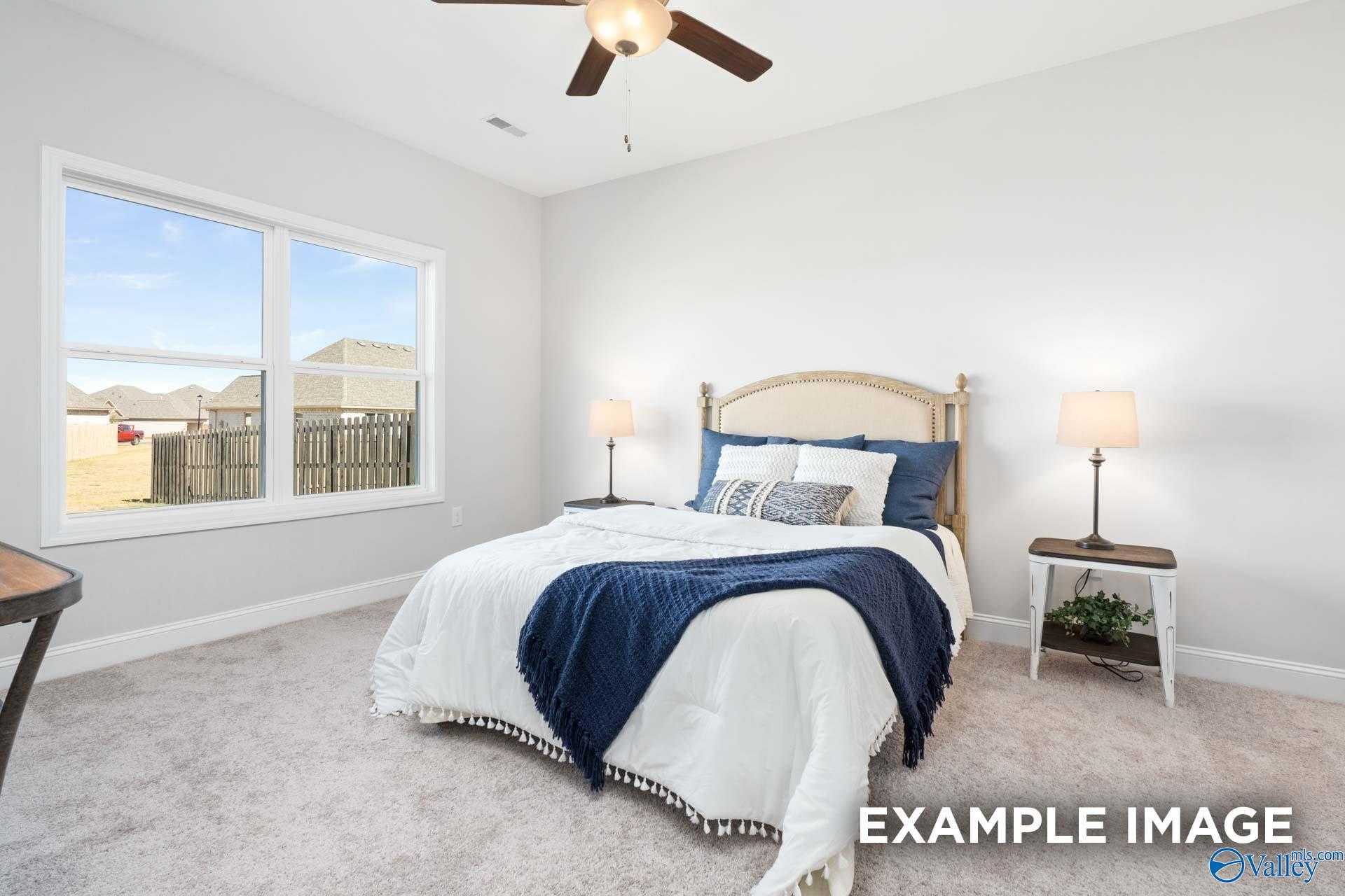 Bright bedroom with large window overlooking neighborhood, ceiling fan, plush bed with navy accents in Davidson Homes The Franklin C, Meridianville, AL