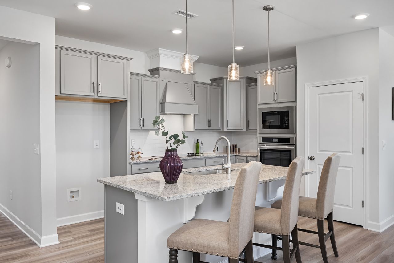 Modern kitchen with granite island and bar seating at Retreat at North Main in Lillington, NC by Davidson Homes.