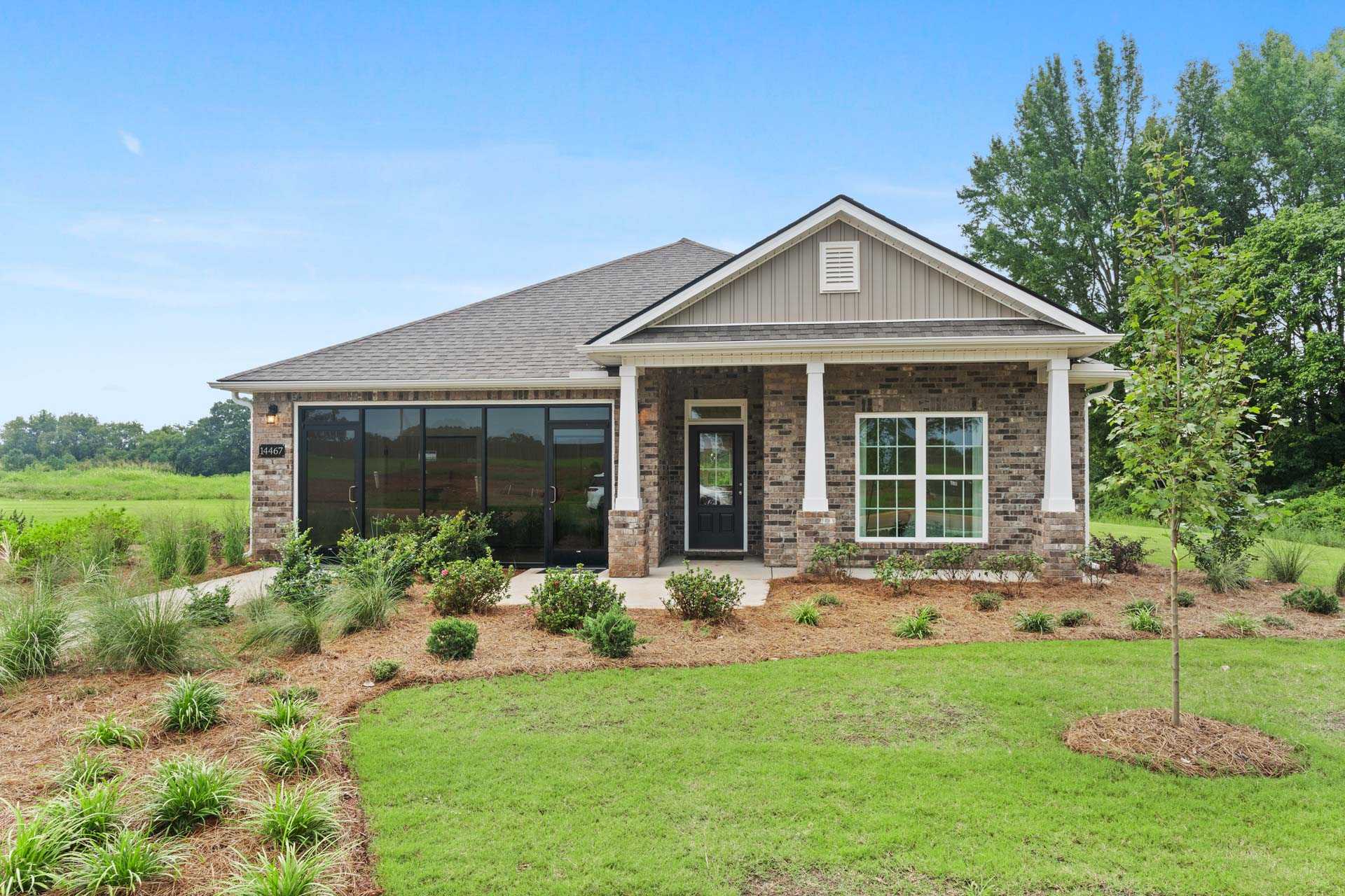 Craftsman-style home exterior at The Meadows in Athens Alabama with covered porch stone accents and landscaped yard