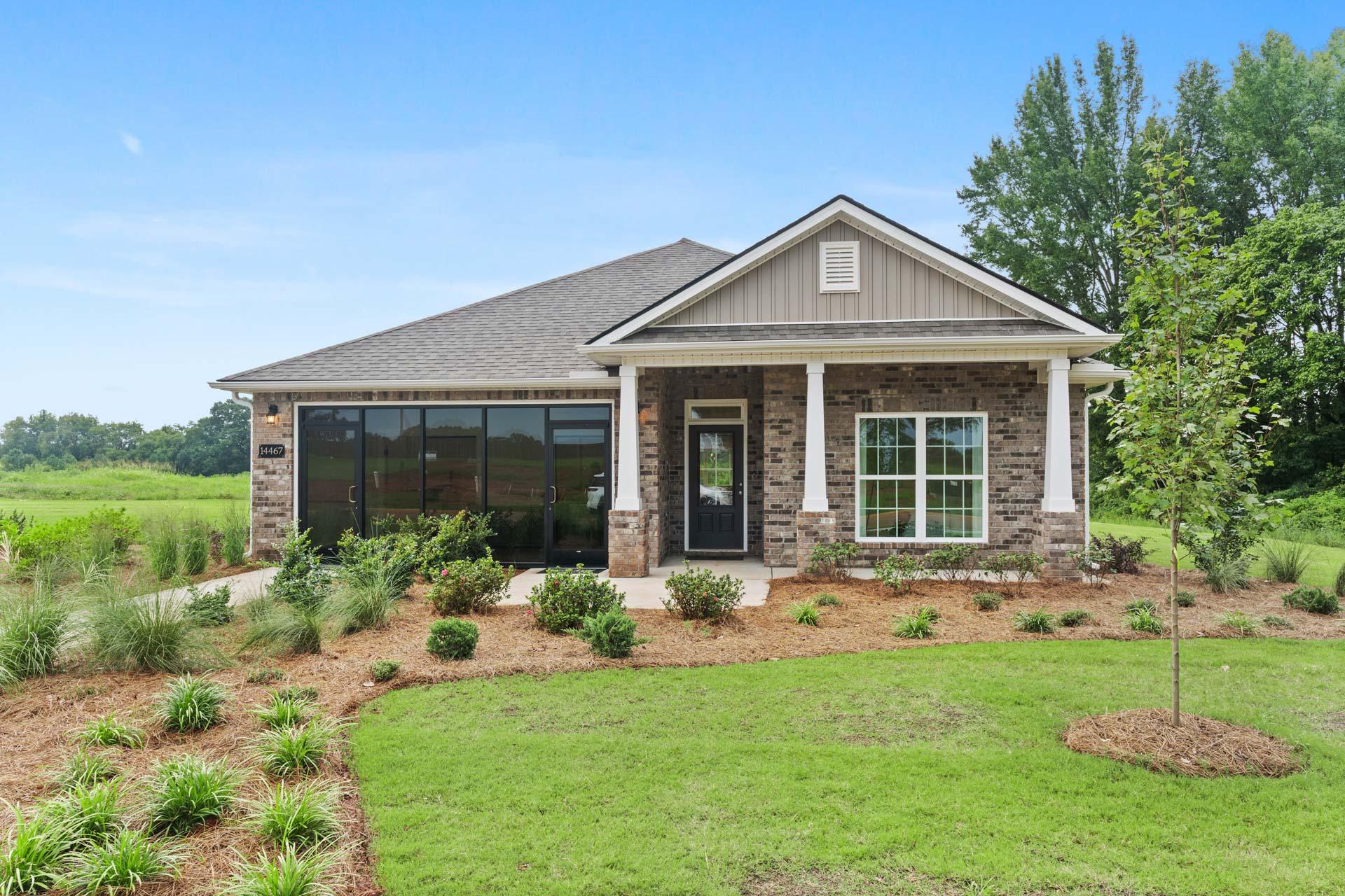 Craftsman-style home exterior at The Meadows in Athens Alabama with covered porch stone accents and landscaped yard