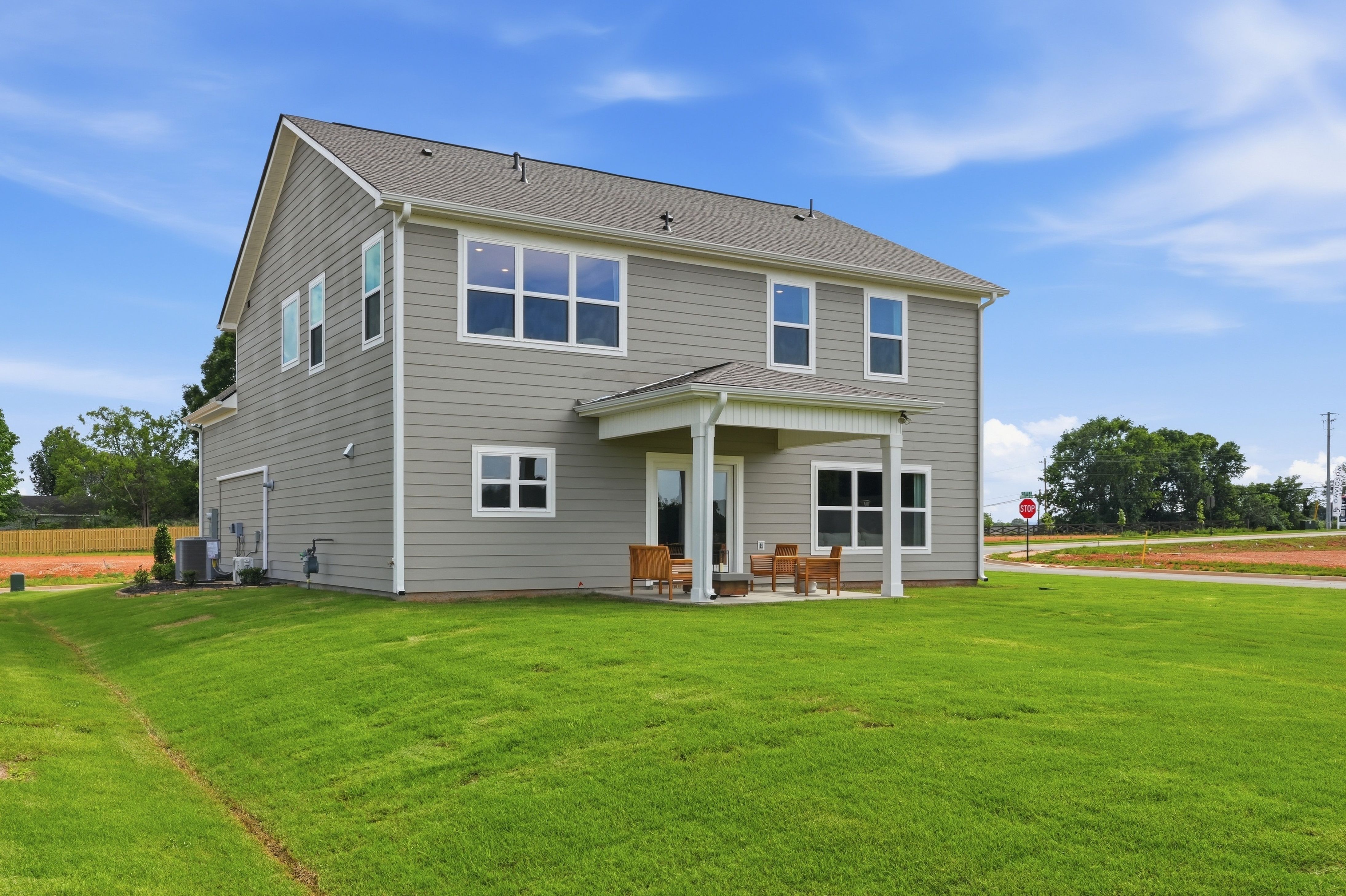 Gray two-story Davidson Homes house exterior at Berry Cove in New Market, Alabama with a covered back patio and large yard.