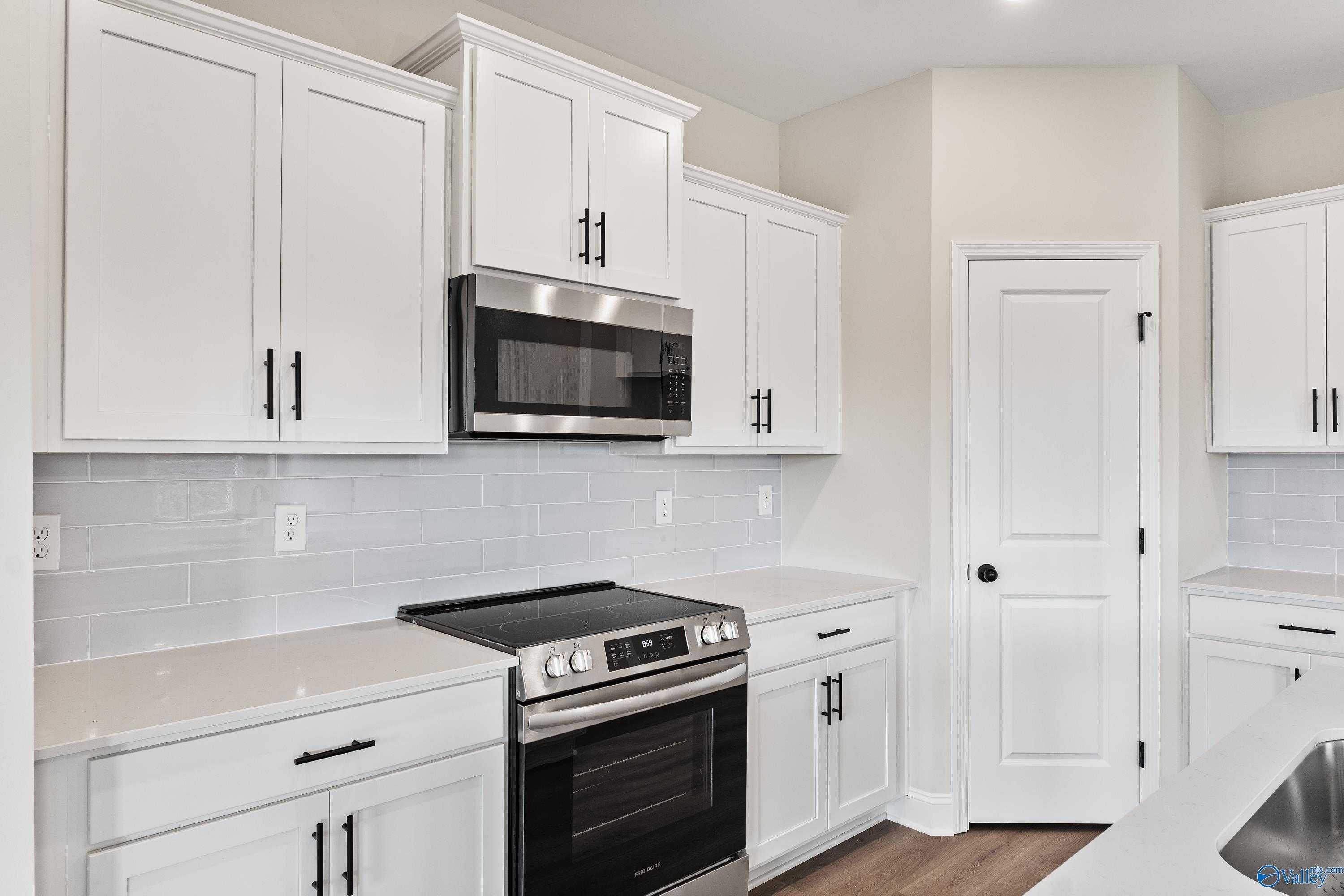 Modern white kitchen featuring stainless steel appliances, subway tile backsplash, and quartz counters in Davidson Homes The Franklin B, Hazel Green, AL