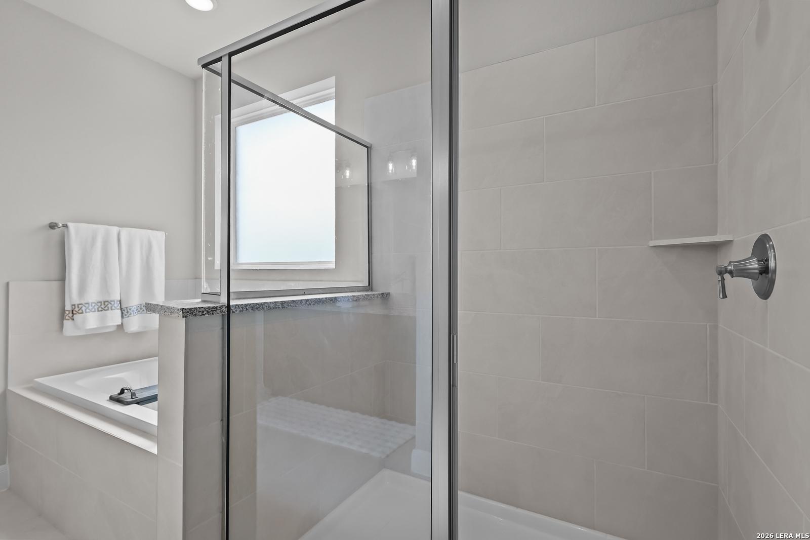 Modern master bathroom featuring frameless glass shower, soaking tub, and tiled accents in Davidson Homes The Rockford G, Ladera, San Antonio
