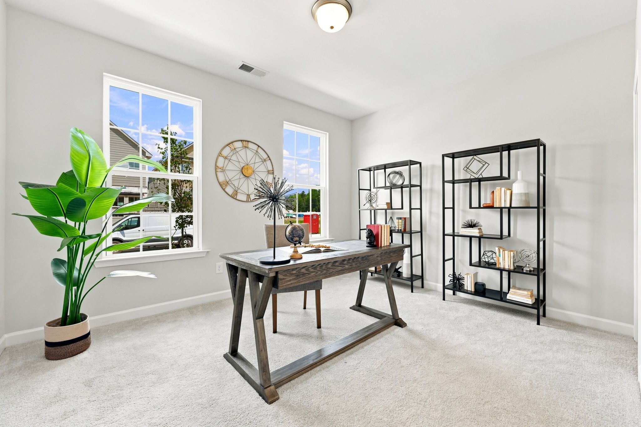 Modern home office in The Jordan A featuring a wooden desk, sleek black shelving, and large windows in Knightdale, NC.