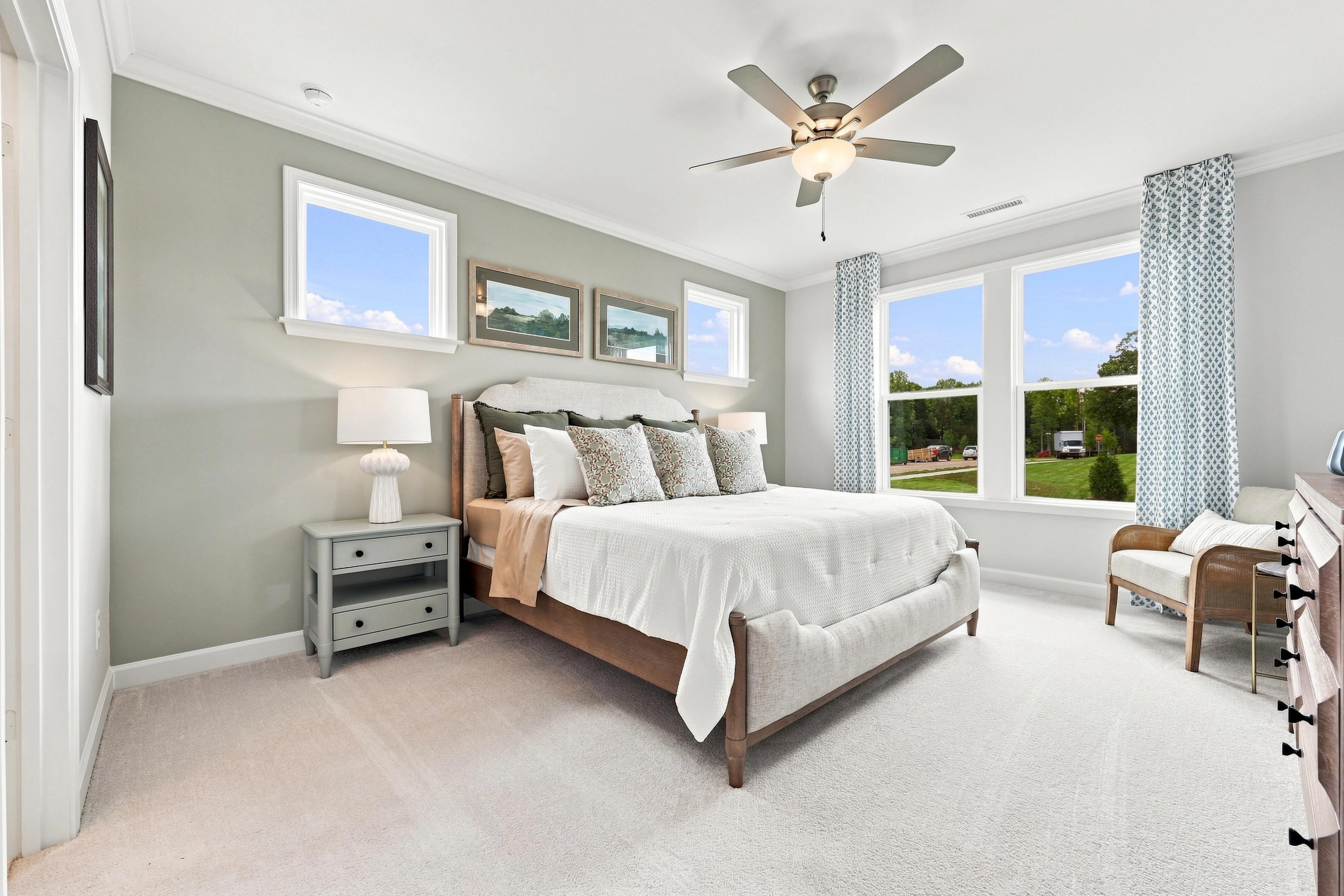 Spacious master suite in The Daphne featuring a comfortable bed, bedside tables, and large windows with natural light.