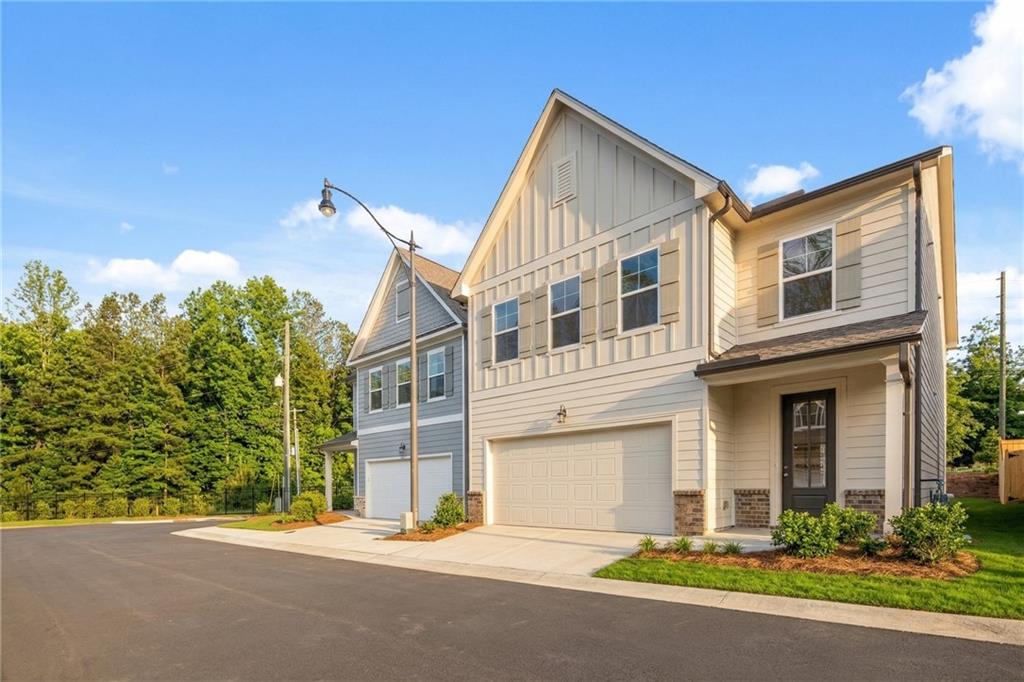 Modern two-story Gavin E home with beige siding, two-car garage, and front porch in The Village at Shallowford, Kennesaw, Georgia