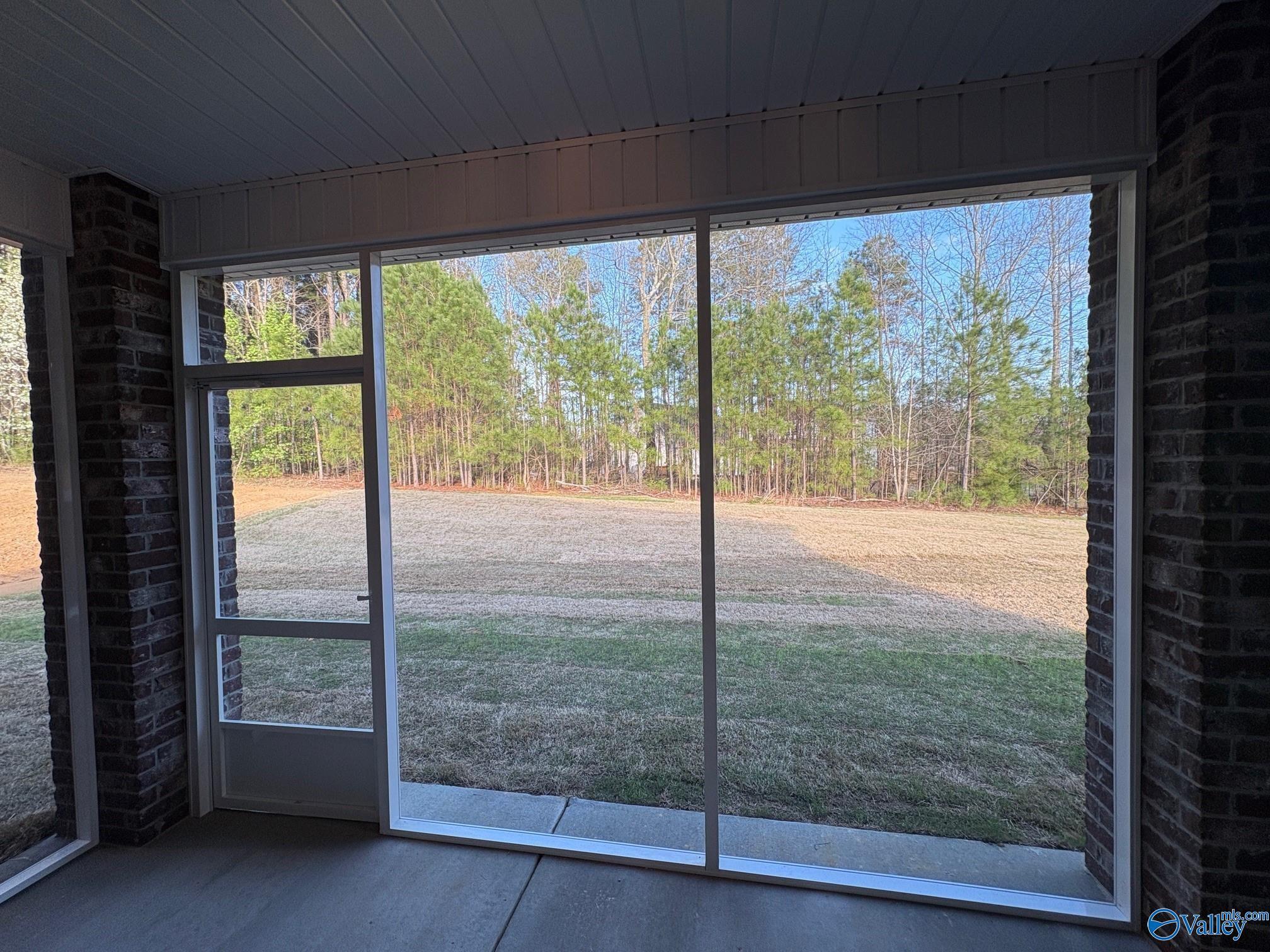 Screened-in back porch with brick walls and wooded yard view in Davidson Homes The Asheville C, Arab, Alabama