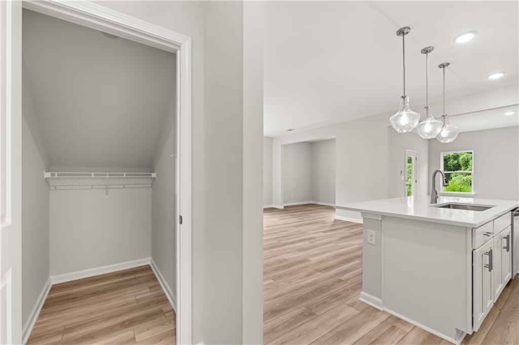 Walk-in pantry storage and modern kitchen island with pendant lighting in The Russell A floor plan, Cedar Farms, Winder, GA.