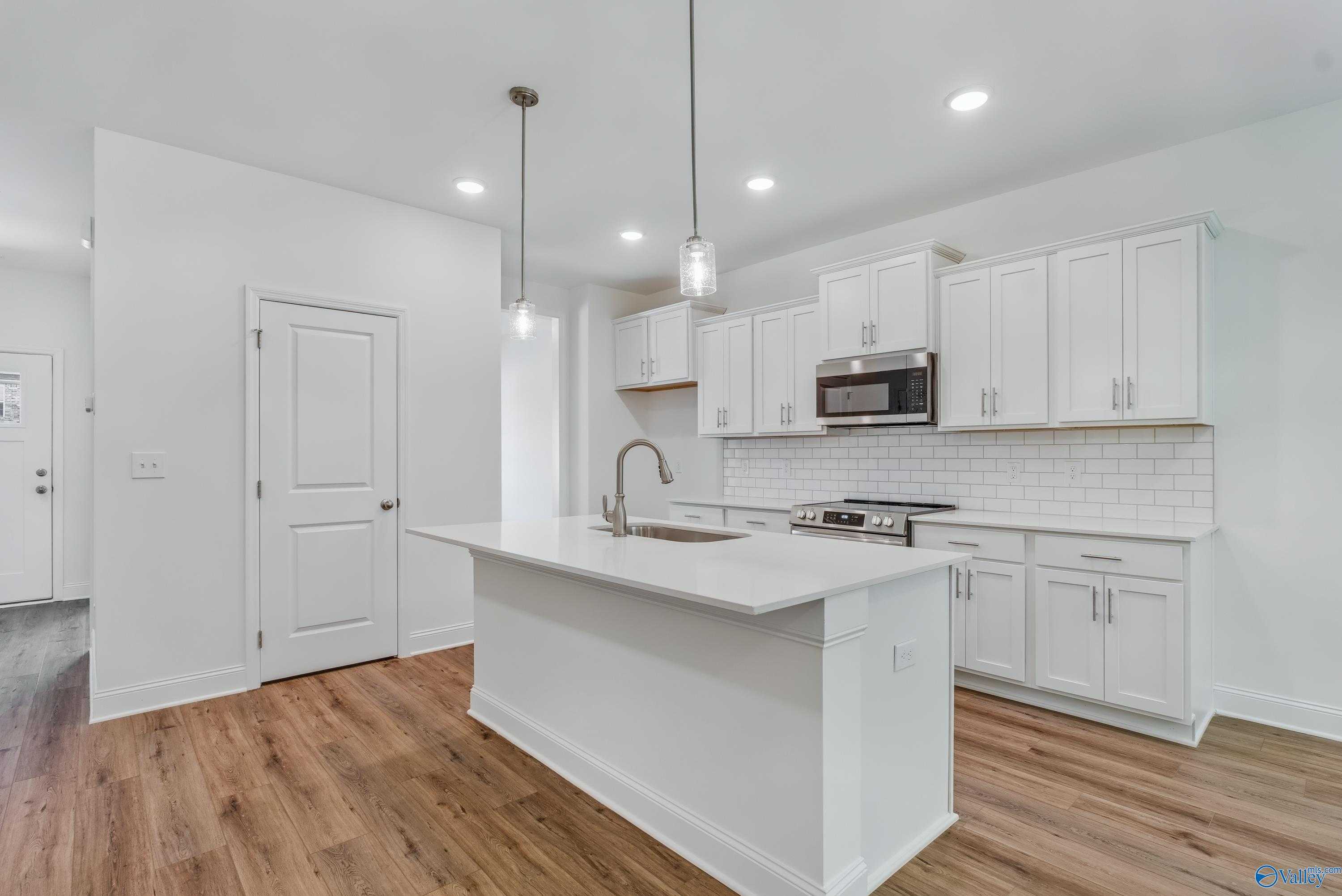 Modern white kitchen with island sink, subway tile backsplash, stainless appliances in Davidson Homes Shelby A, Arab, Alabama