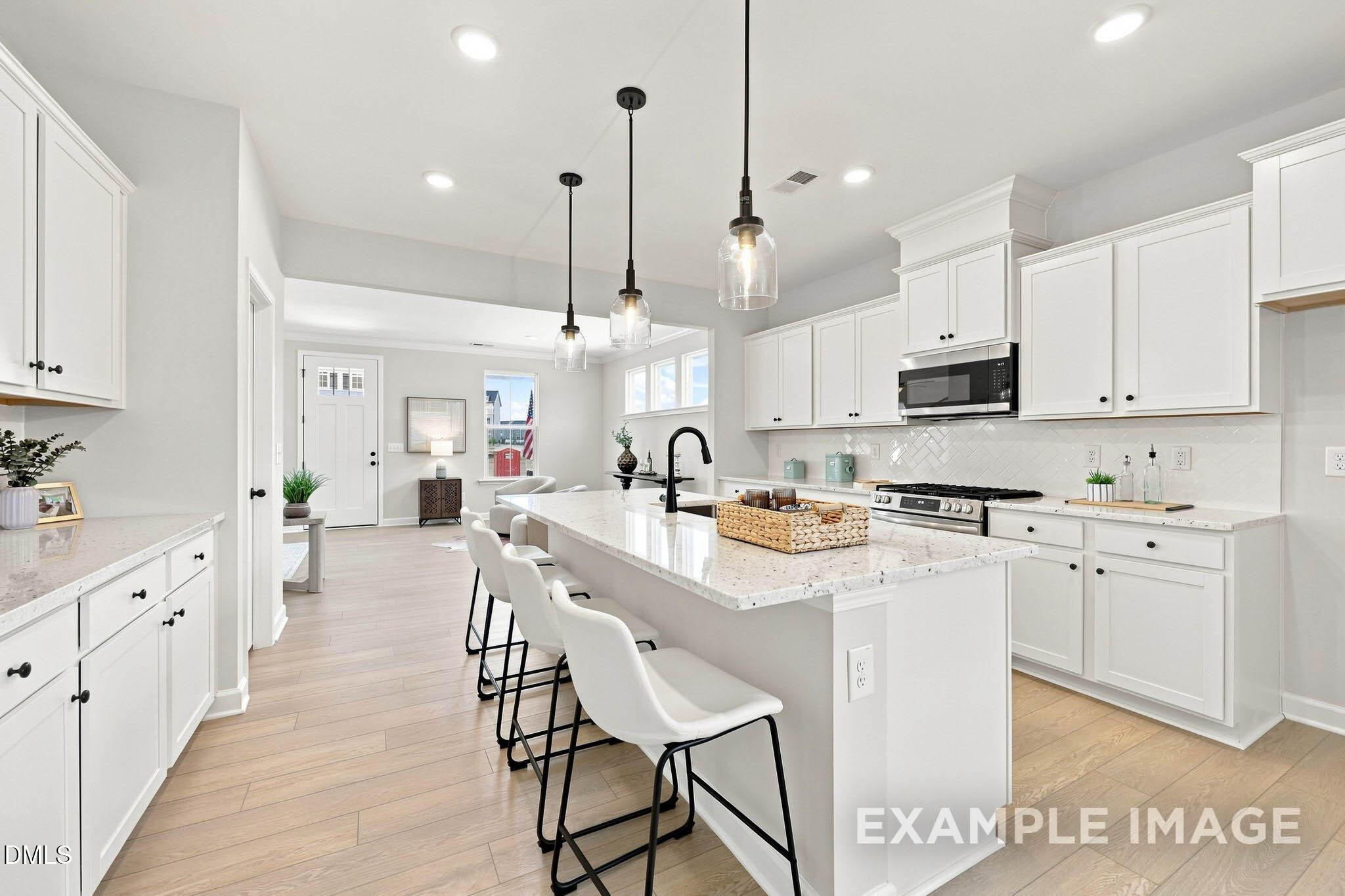 Bright white kitchen with island, pendant lights, and stainless appliances in Davidson Homes The Harris A plan, Knightdale, NC