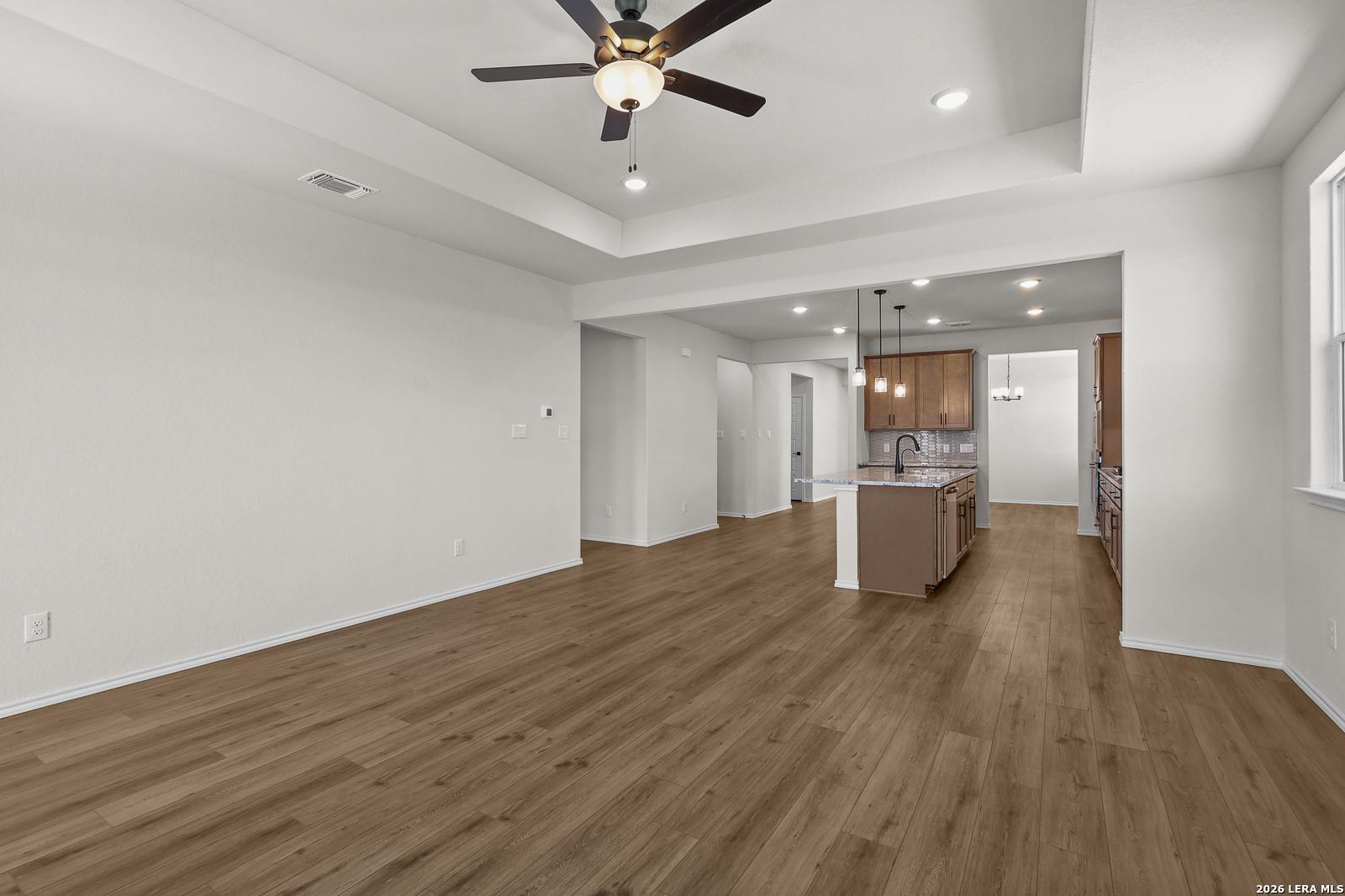 Open-concept living room and kitchen with wood-look flooring in Davidson Homes The Glenwood E, Comanche Ridge, San Antonio