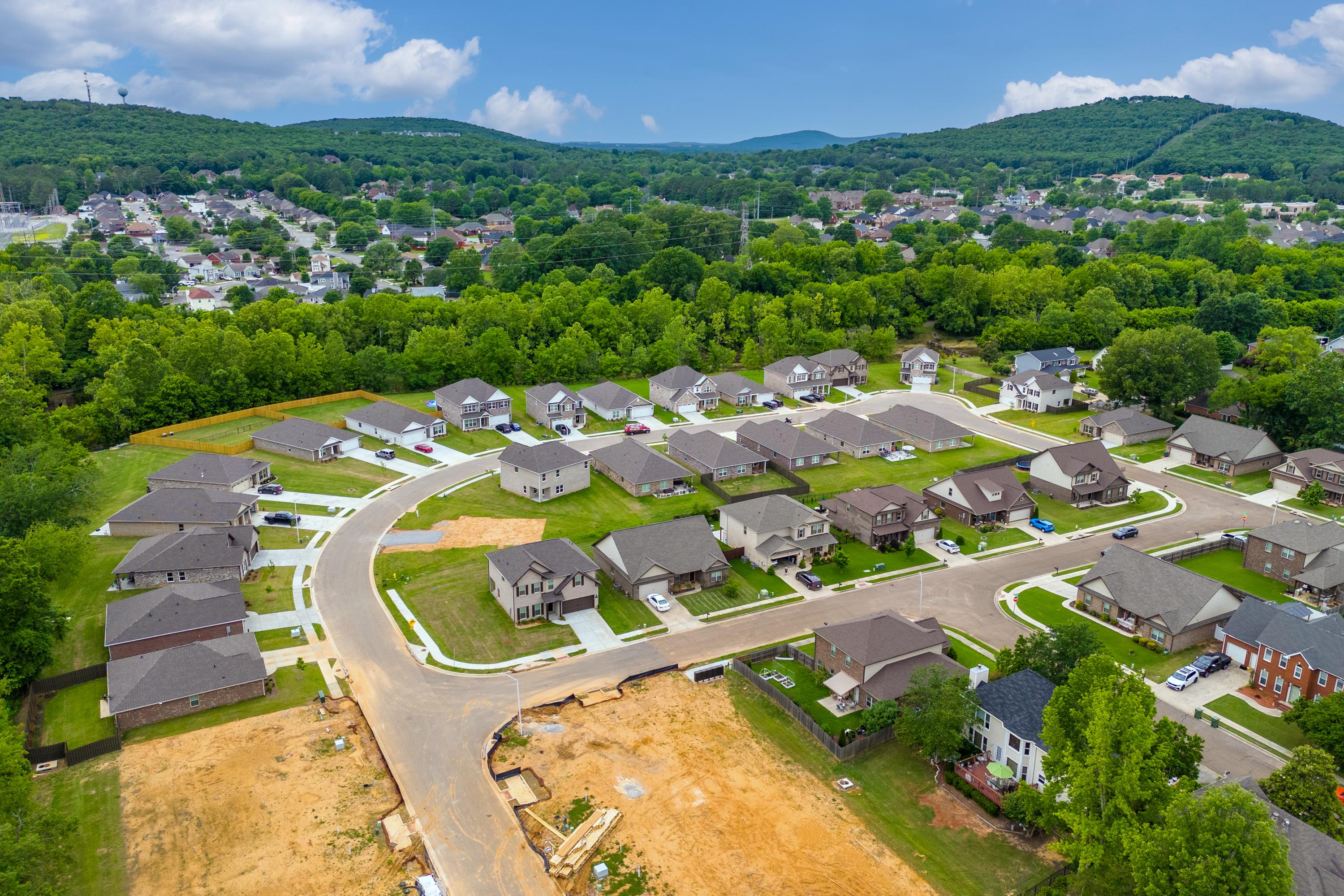 Aerial view of Pavilion neighborhood in Huntsville AL by Davidson Homes featuring new single-family homes, curved streets, and surrounding hills