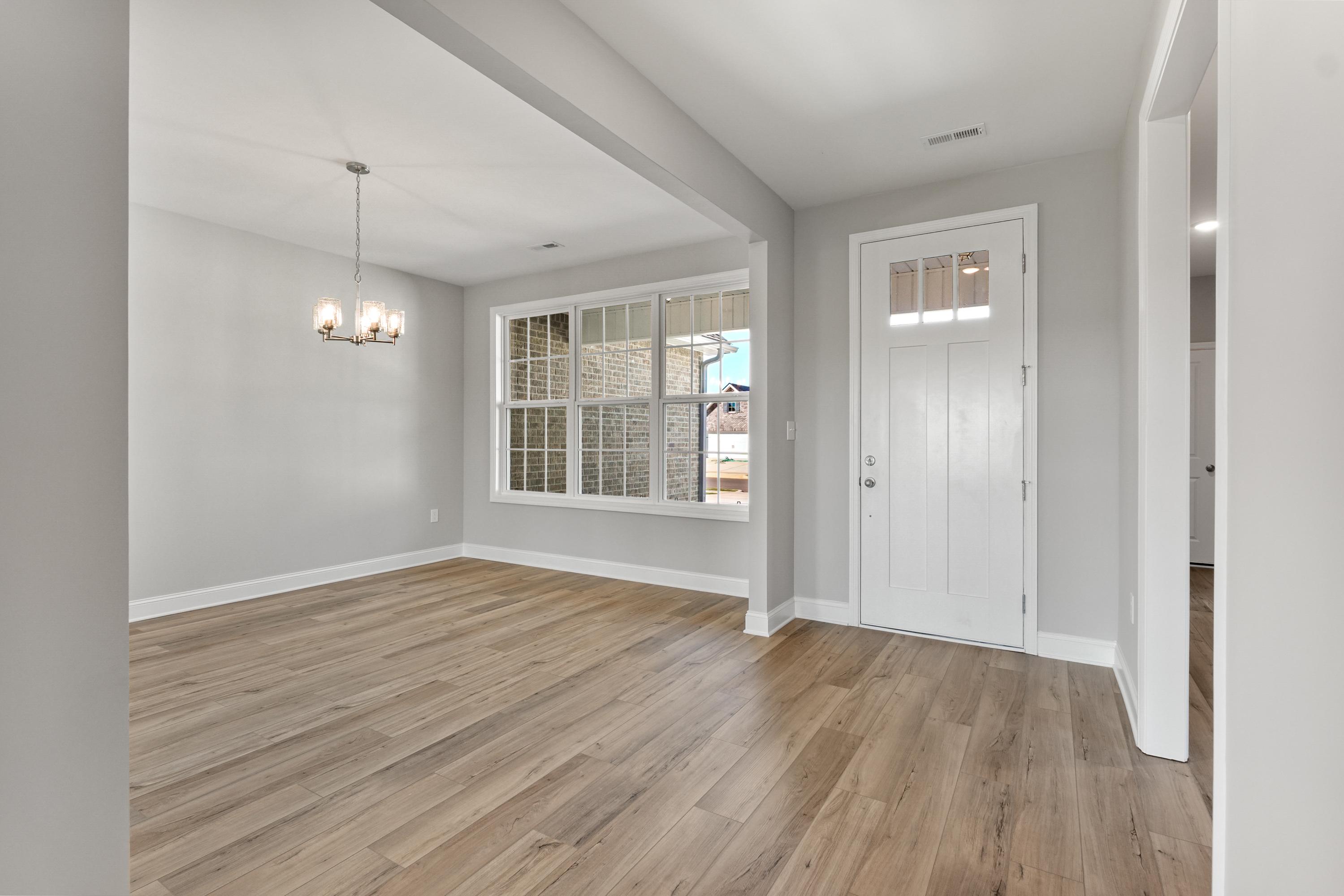 Spacious entryway in The Valencia home design by Davidson Homes featuring light gray walls, oak hardwood floors, chandelier, and large window view