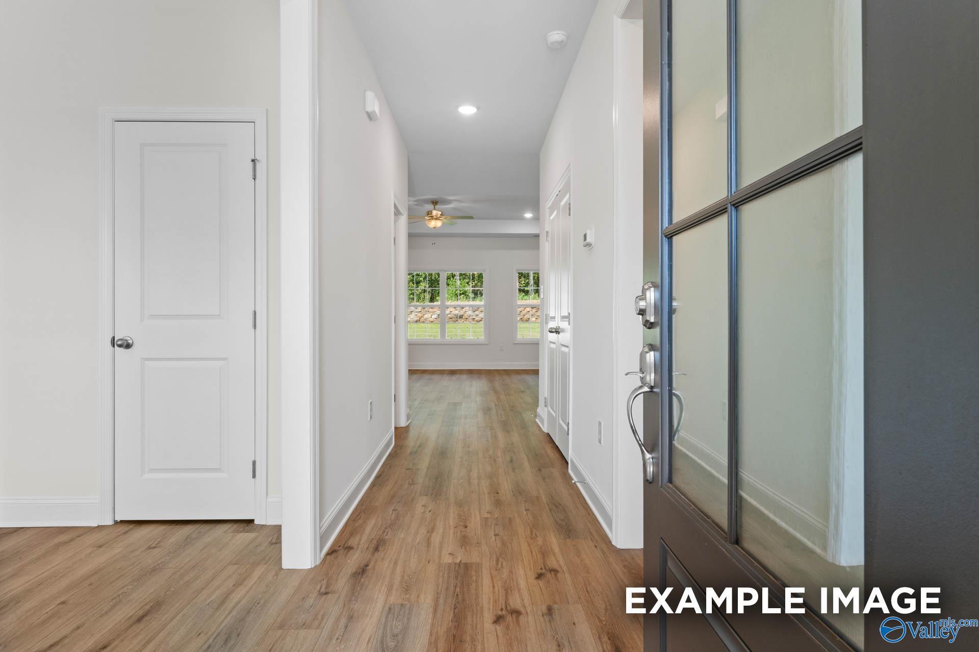 Bright hallway with hardwood floors, white doors, and ceiling fan in The Rockford C 3-bedroom home, Madison, Alabama