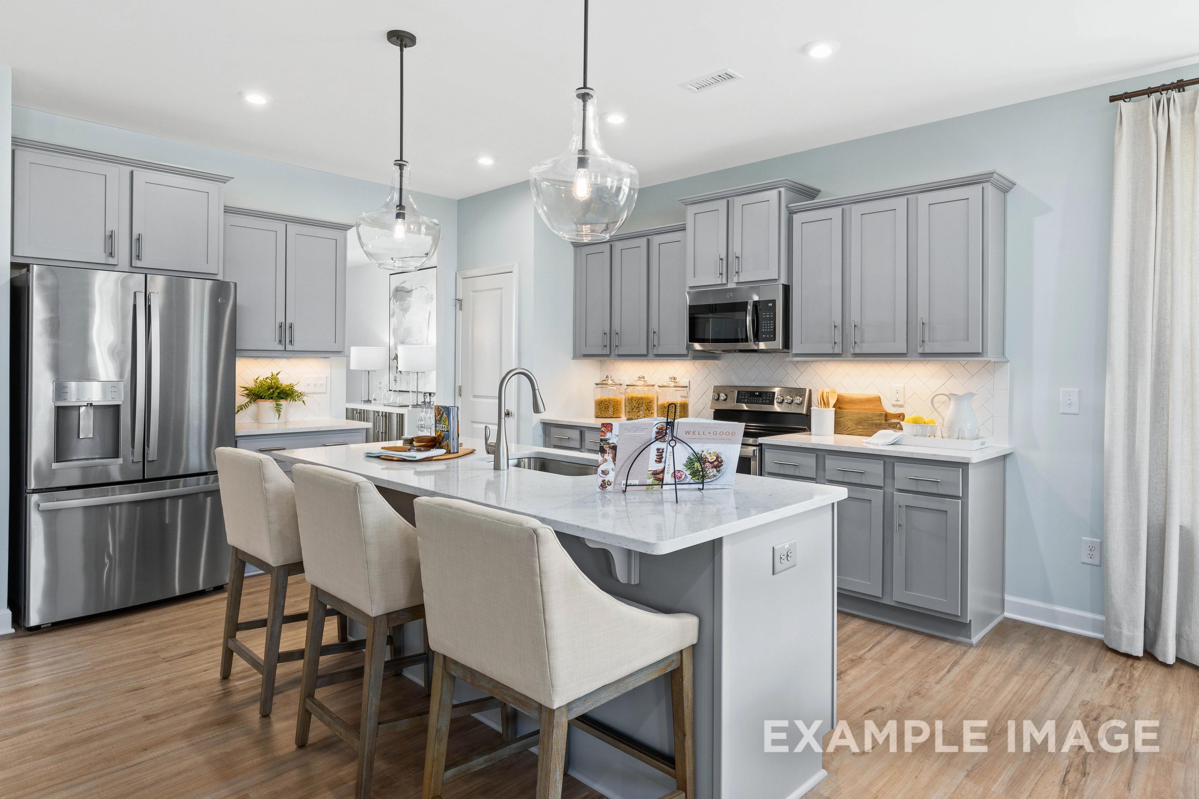 Modern kitchen in The Ash C by Davidson Homes featuring gray shaker cabinets, white island, stainless appliances