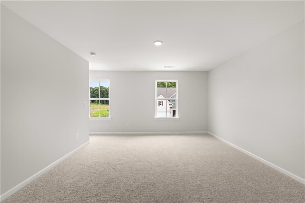 Spacious carpeted bonus room with large windows in The Sinclair B floor plan by Davidson Homes in Cedar Farms, Winder, GA.