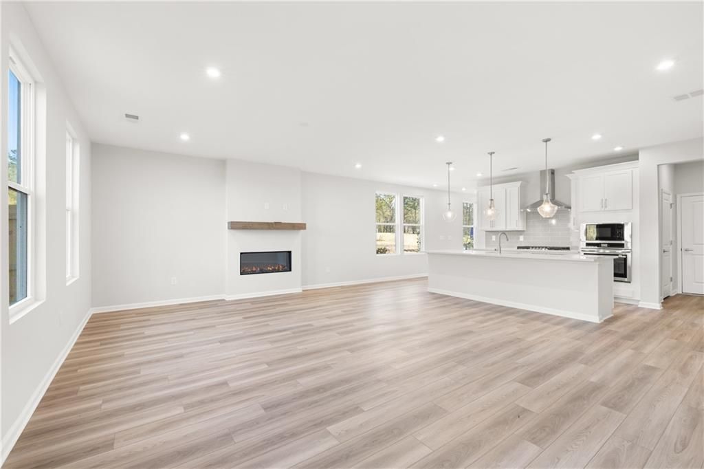 Open-concept living area featuring linear gas fireplace, white kitchen island, and large windows in Davidson Homes The Cary A, Winder, GA