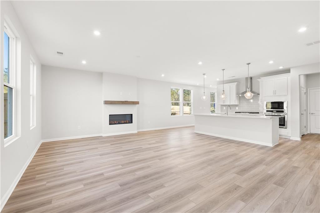 Open-concept living area featuring linear gas fireplace, white kitchen island, and large windows in Davidson Homes The Cary A, Winder, GA