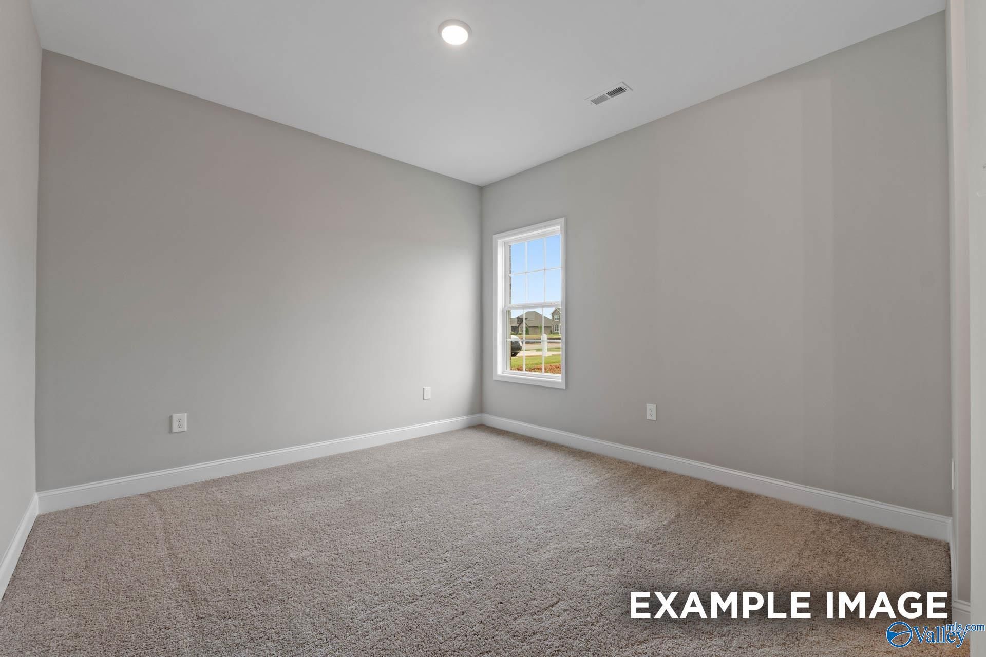 Empty secondary bedroom featuring gray walls, beige carpet, and window to backyard in Davidson Homes The Finleigh, Harvest, Alabama