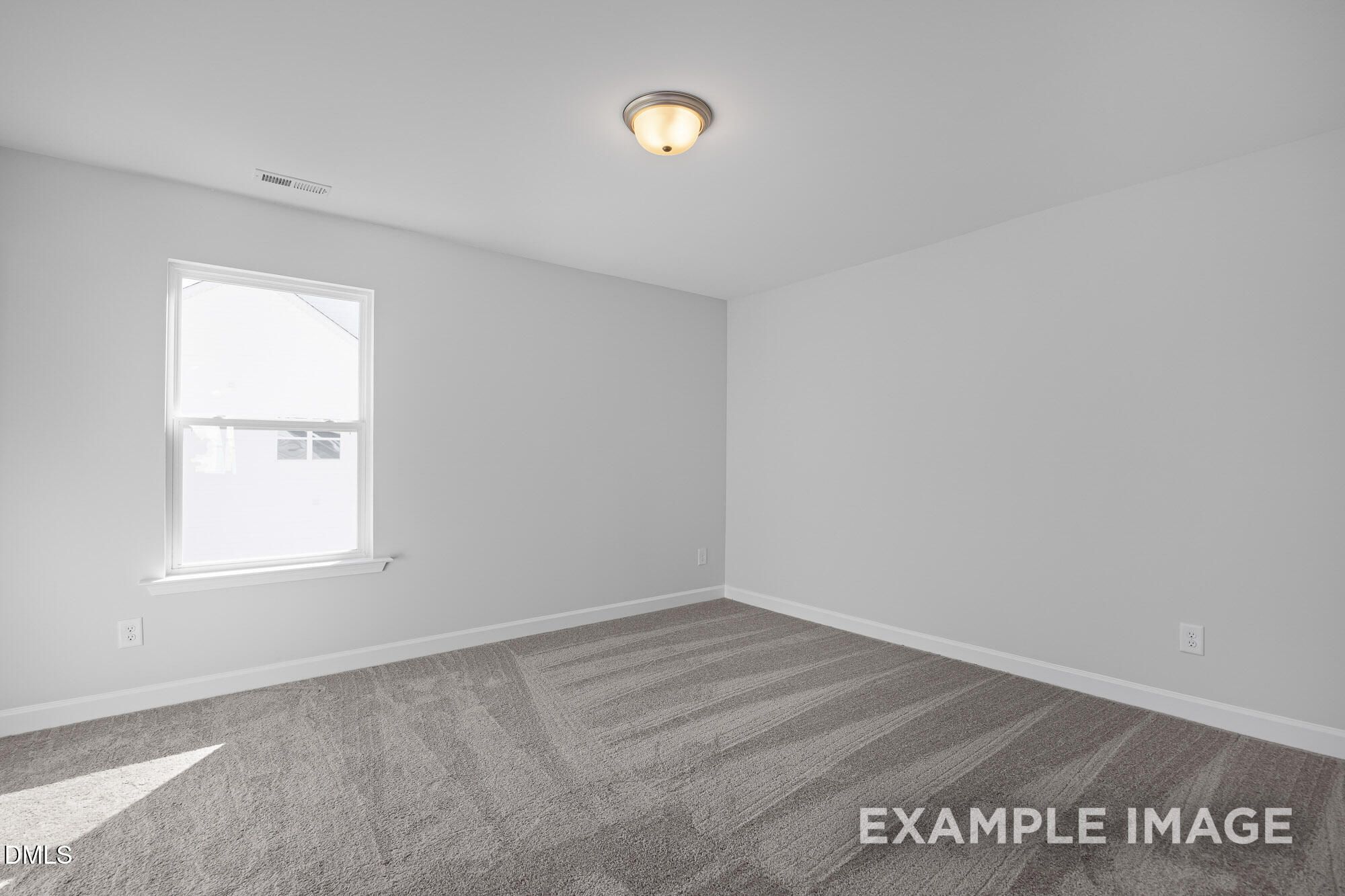 Empty bedroom with light gray walls, plush carpet flooring, and sunny window in Davidson Homes The Cypress B II, Angier, NC