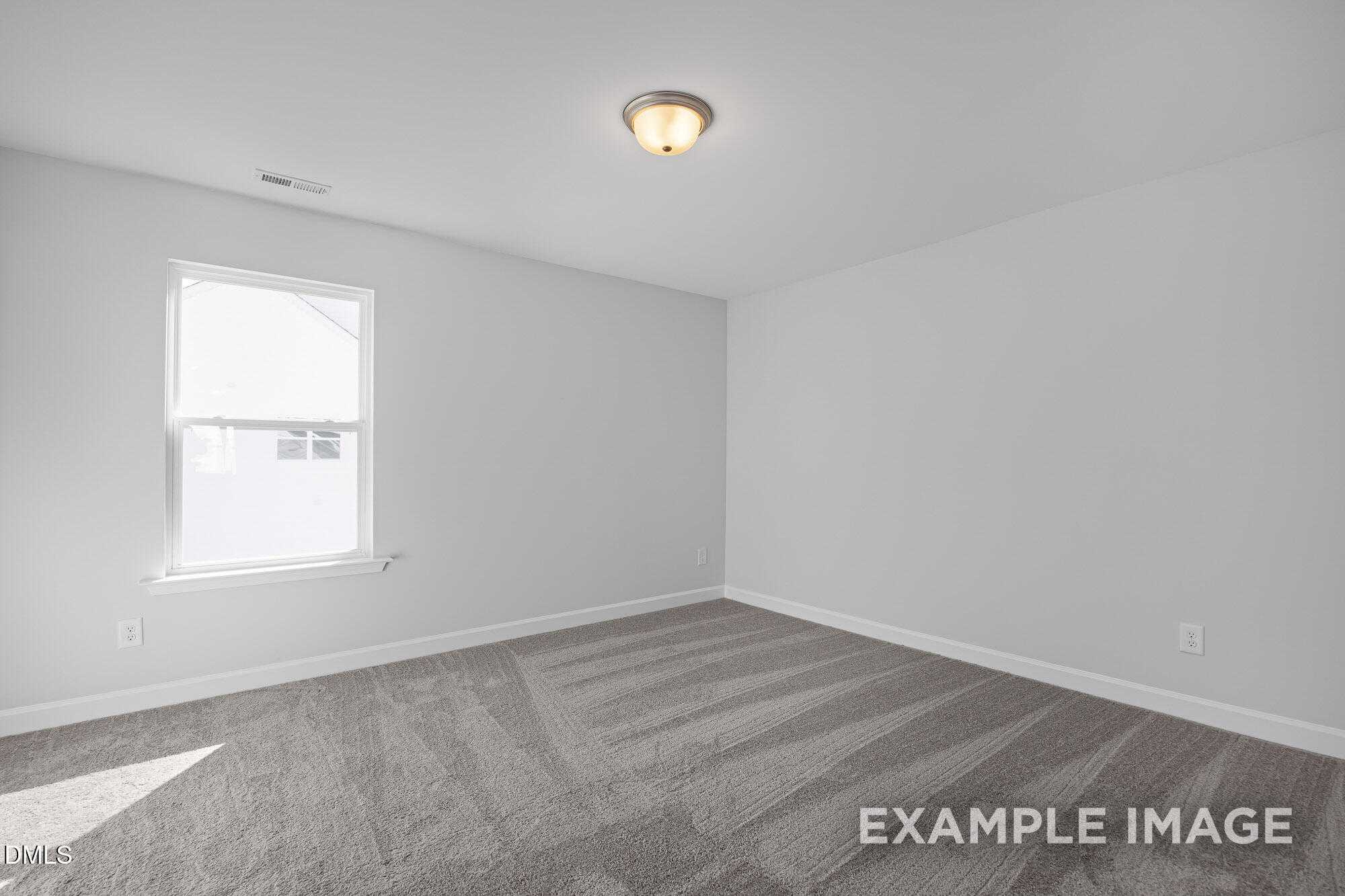 Empty bedroom with light gray walls, plush carpet flooring, and sunny window in Davidson Homes The Cypress B II, Angier, NC