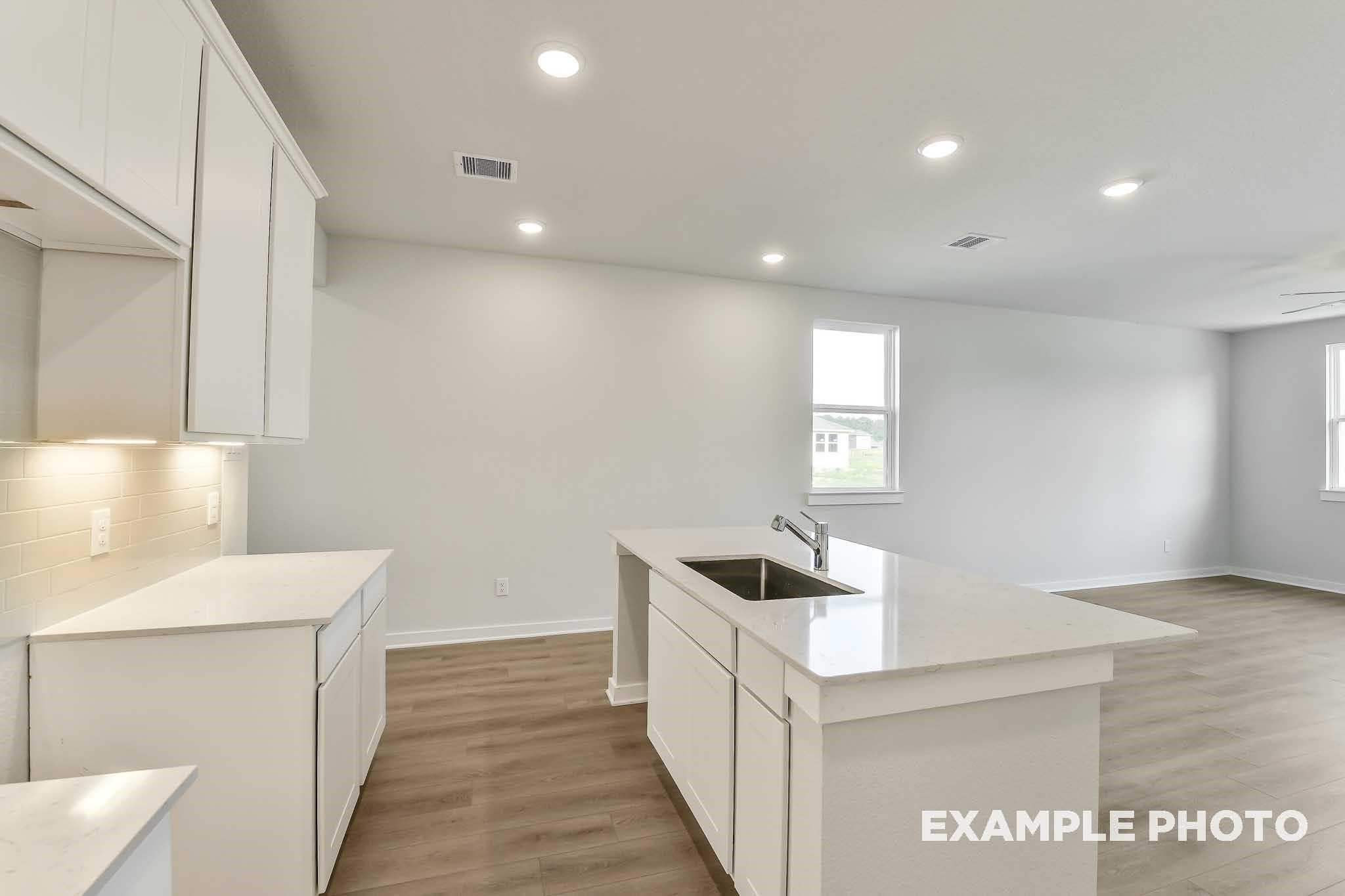 Bright open-concept kitchen with white cabinets, quartz island sink, and hardwood floors in Davidson Homes The Colorado F, Conroe, TX