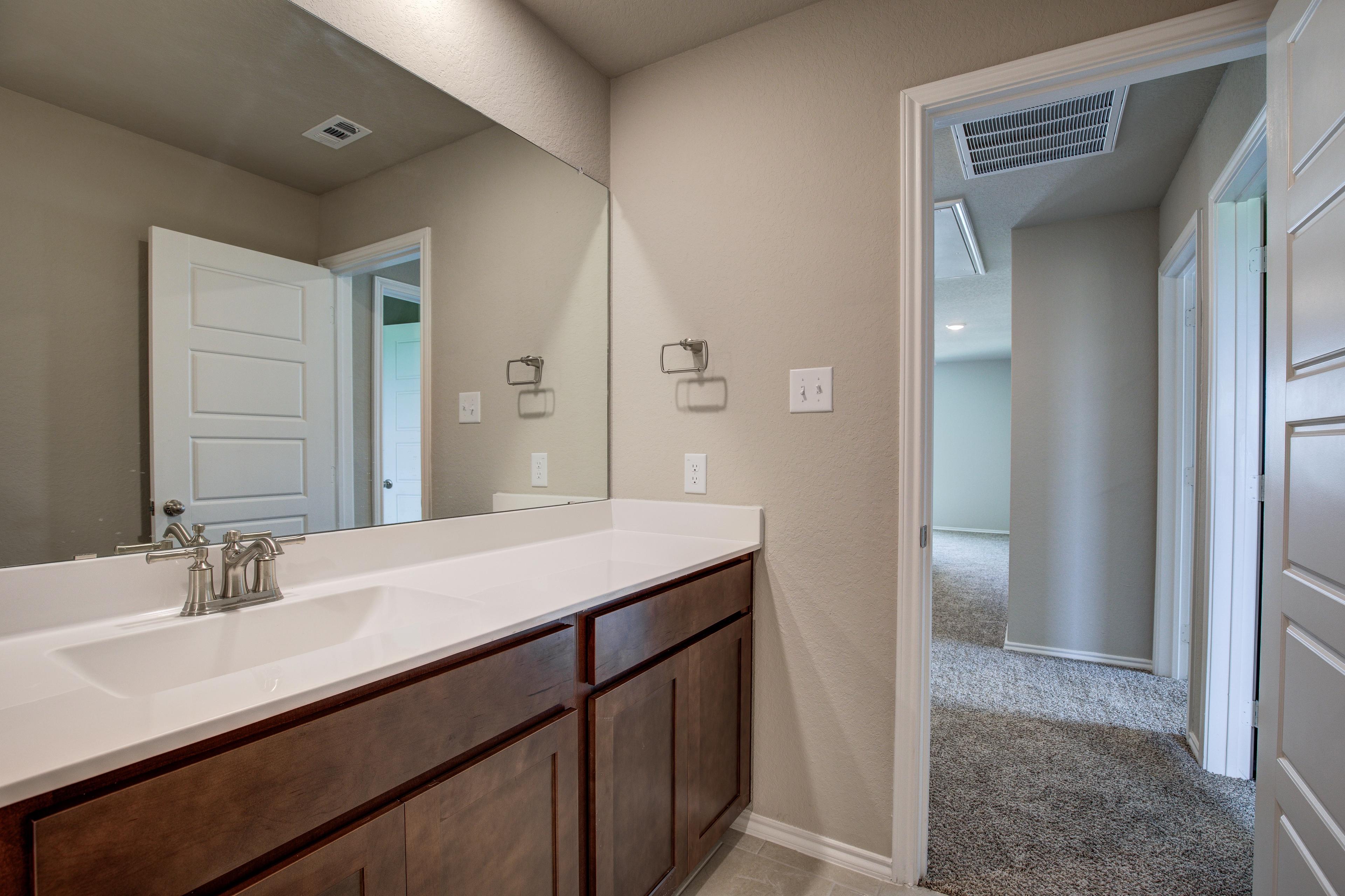 The Murray G master bathroom vanity with white countertop, single sink, large mirror, and shaker cabinets in San Antonio
