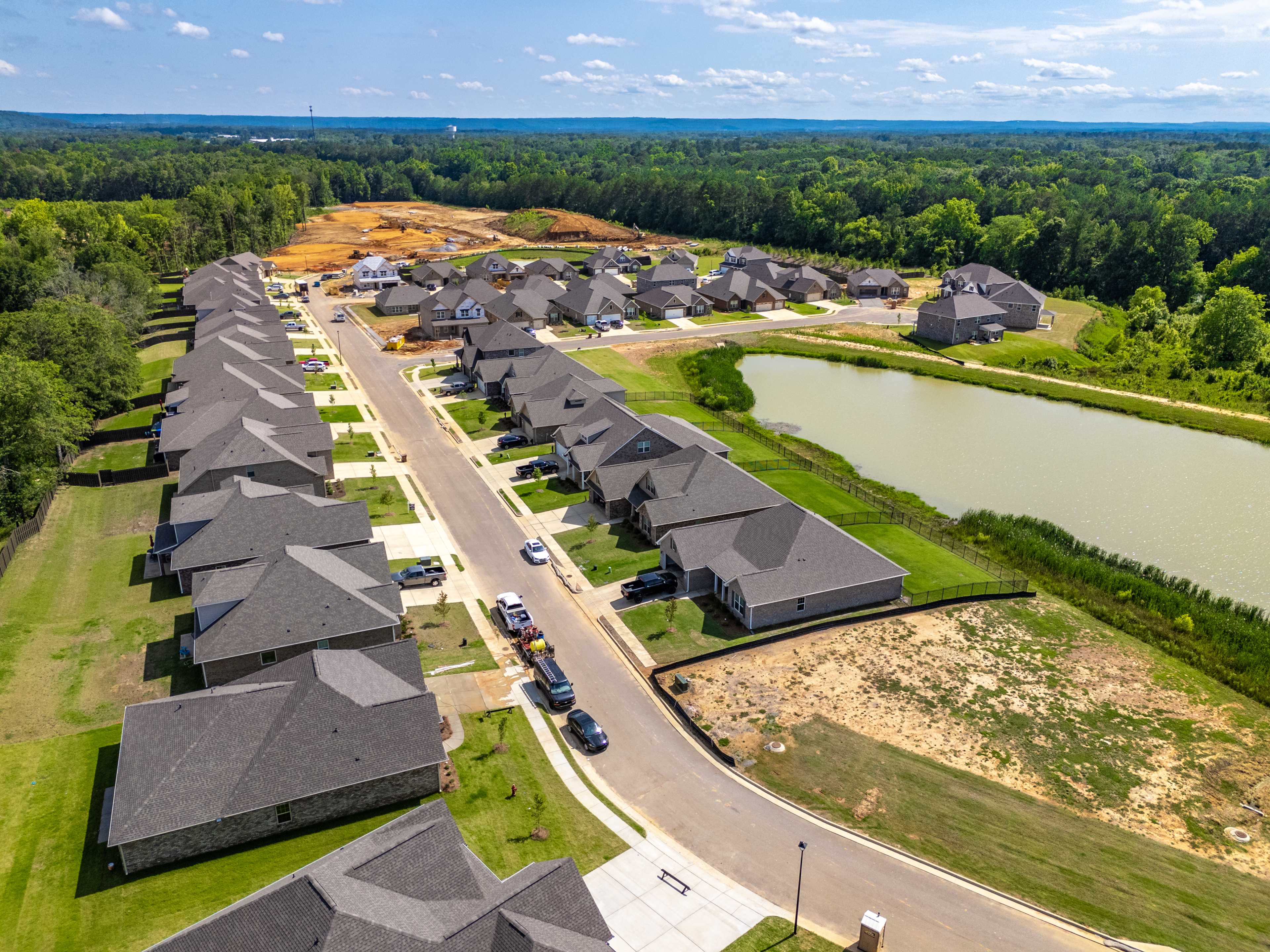 Aerial view of Cain Park neighborhood in Hartselle Alabama with new homes, scenic pond, streets and wooded surroundings
