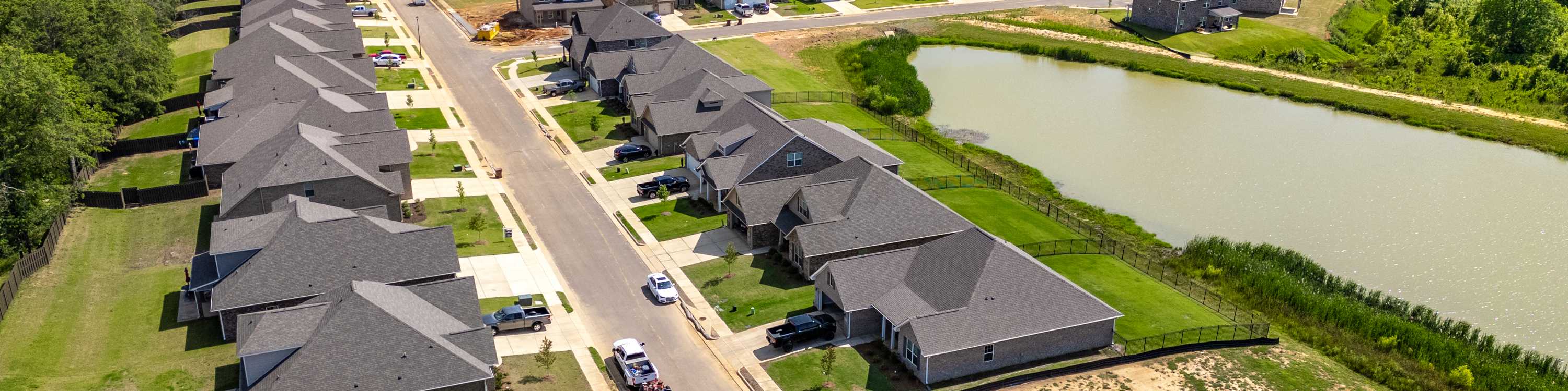 Aerial view of Cain Park neighborhood in Hartselle Alabama with new homes, scenic pond, streets and wooded surroundings