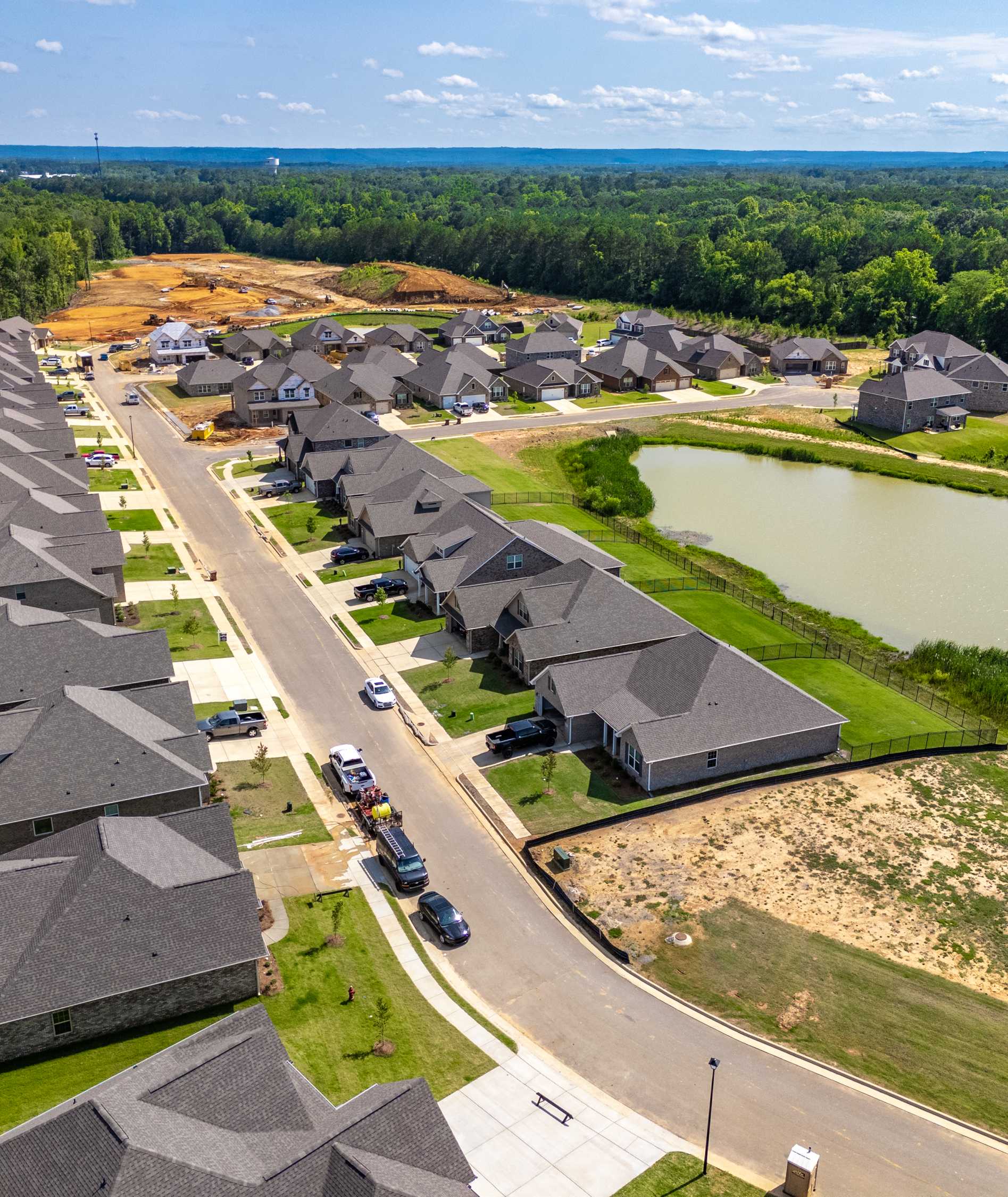 Aerial view of Cain Park neighborhood in Hartselle Alabama with new homes, scenic pond, streets and wooded surroundings