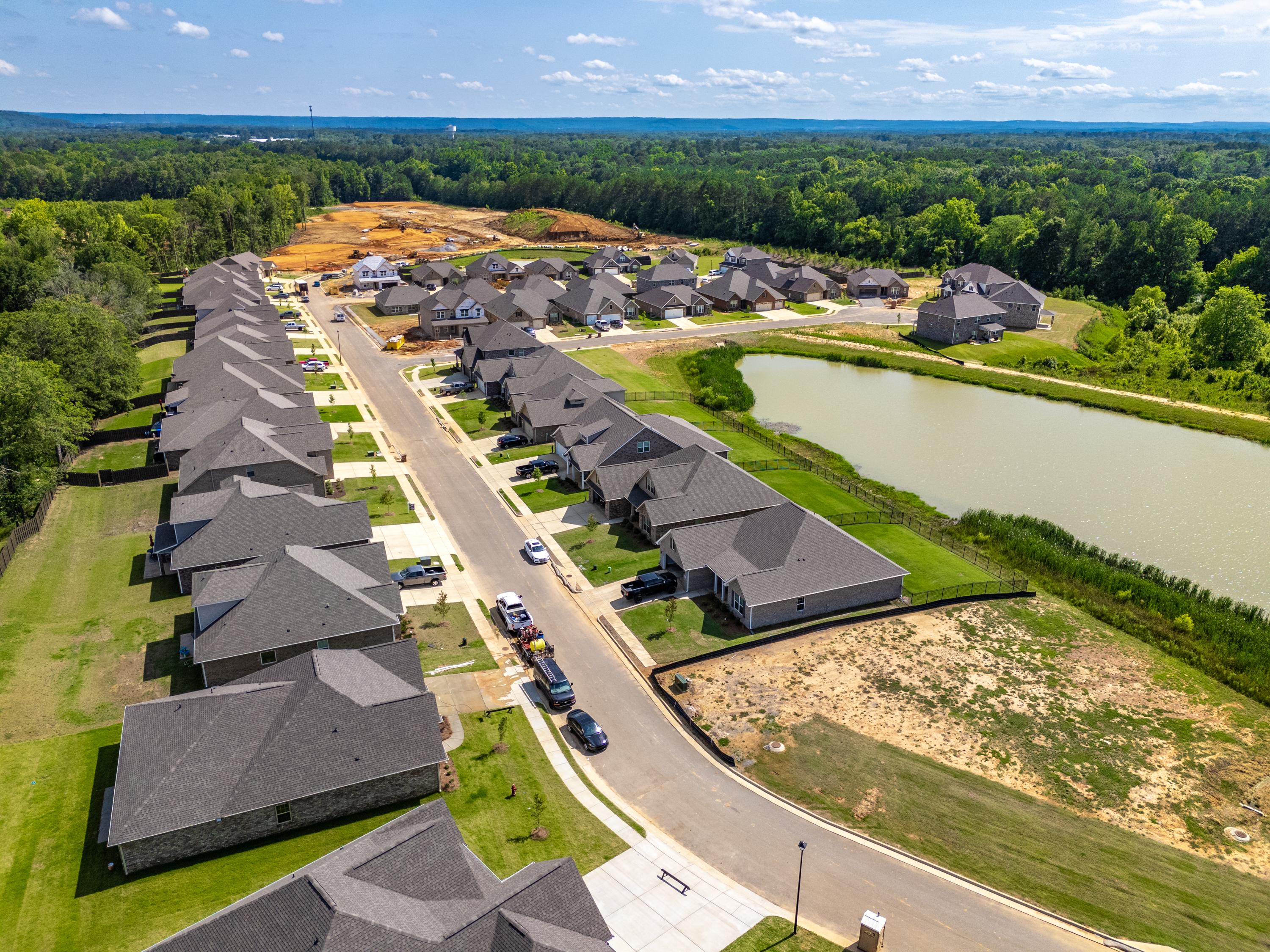 Aerial view of Cain Park neighborhood in Hartselle Alabama with new homes, scenic pond, streets and wooded surroundings